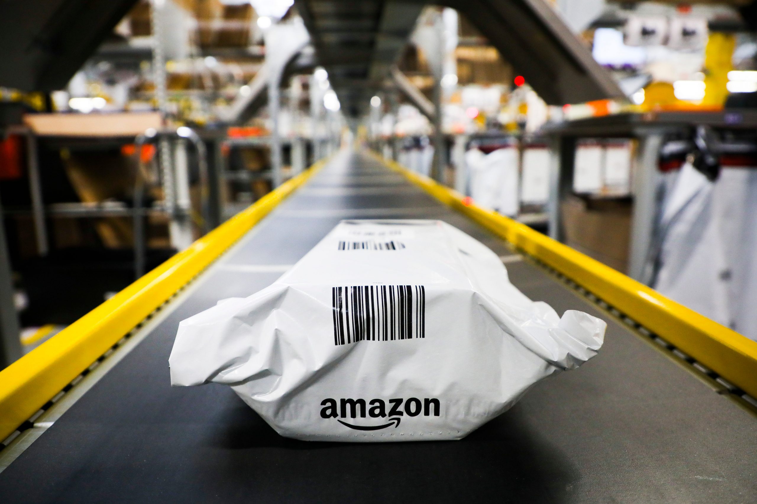 A white Amazon package with a black barcode on a conveyor belt