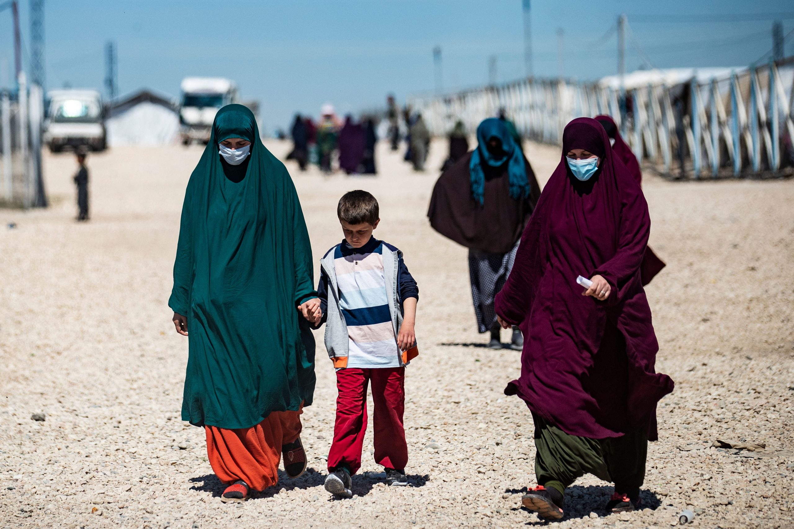 Women with children walk at Camp Roj in northeastern Syria, where relatives of people suspected of belonging to the Islamic State (IS) group are held,