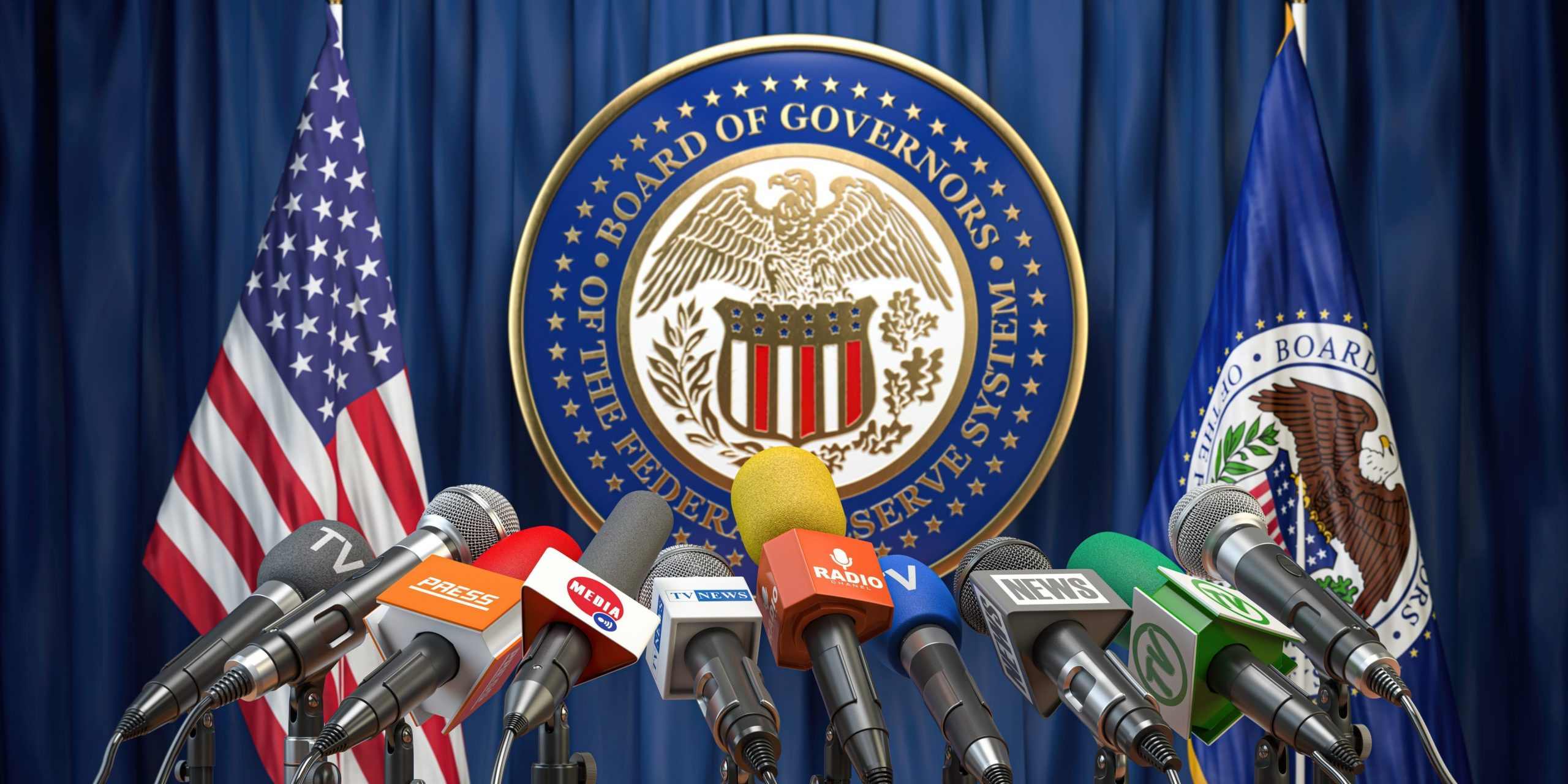 Microphones from TV and radio channels on a podium pointed toward the symbol of the US Federal Reserve and two flags.