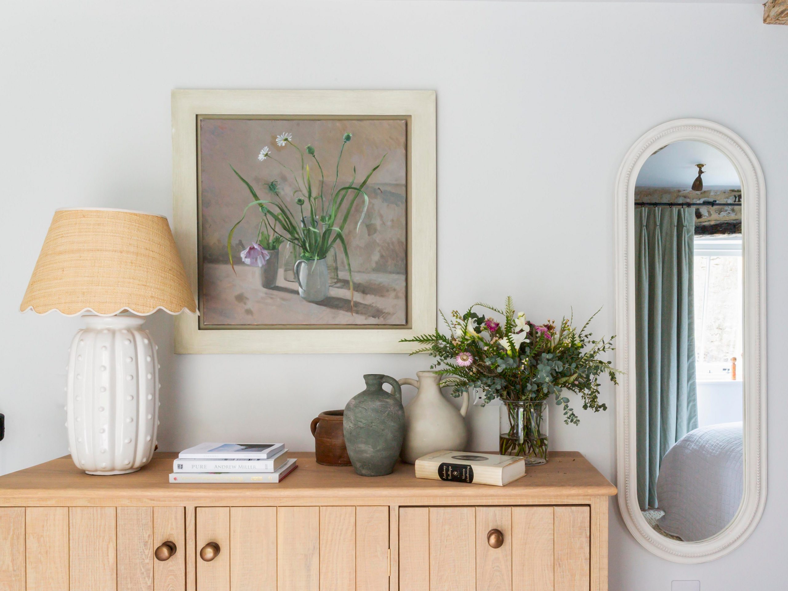 A light brown table, with a plant and lamp on top.