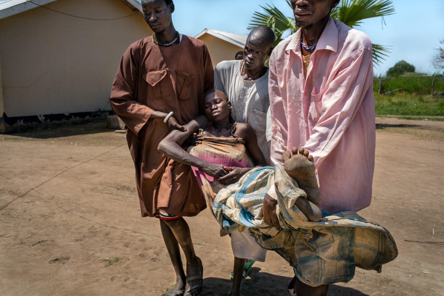 Three men carry a person who has fallen unconscious.
