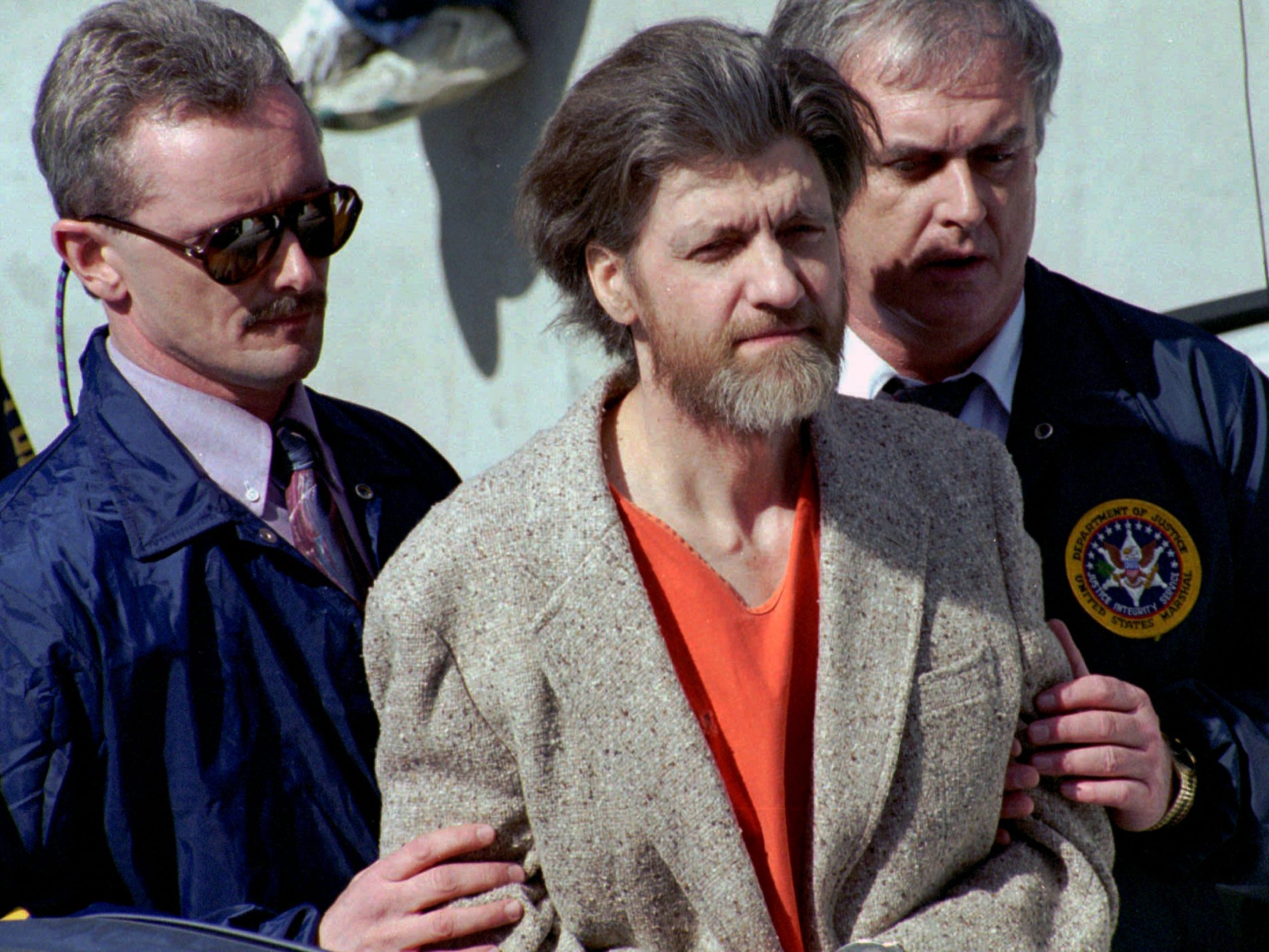 In this April 4, 1996 file photo, Ted Kaczynski, better known as the Unabomber, is flanked by federal agents as he is led to a car from the federal courthouse in Helena, Mont.