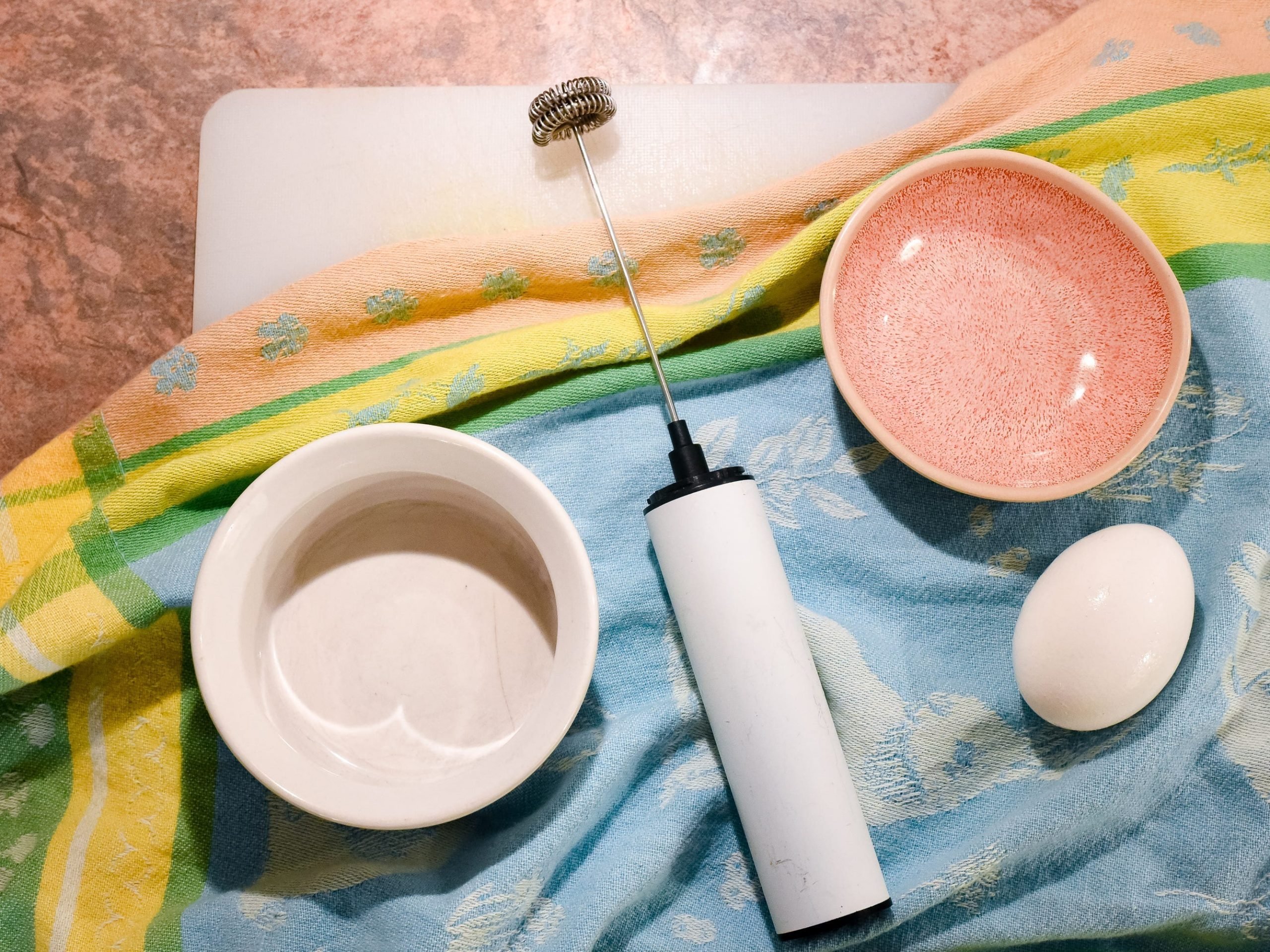 An egg, a frother, and two bowls.