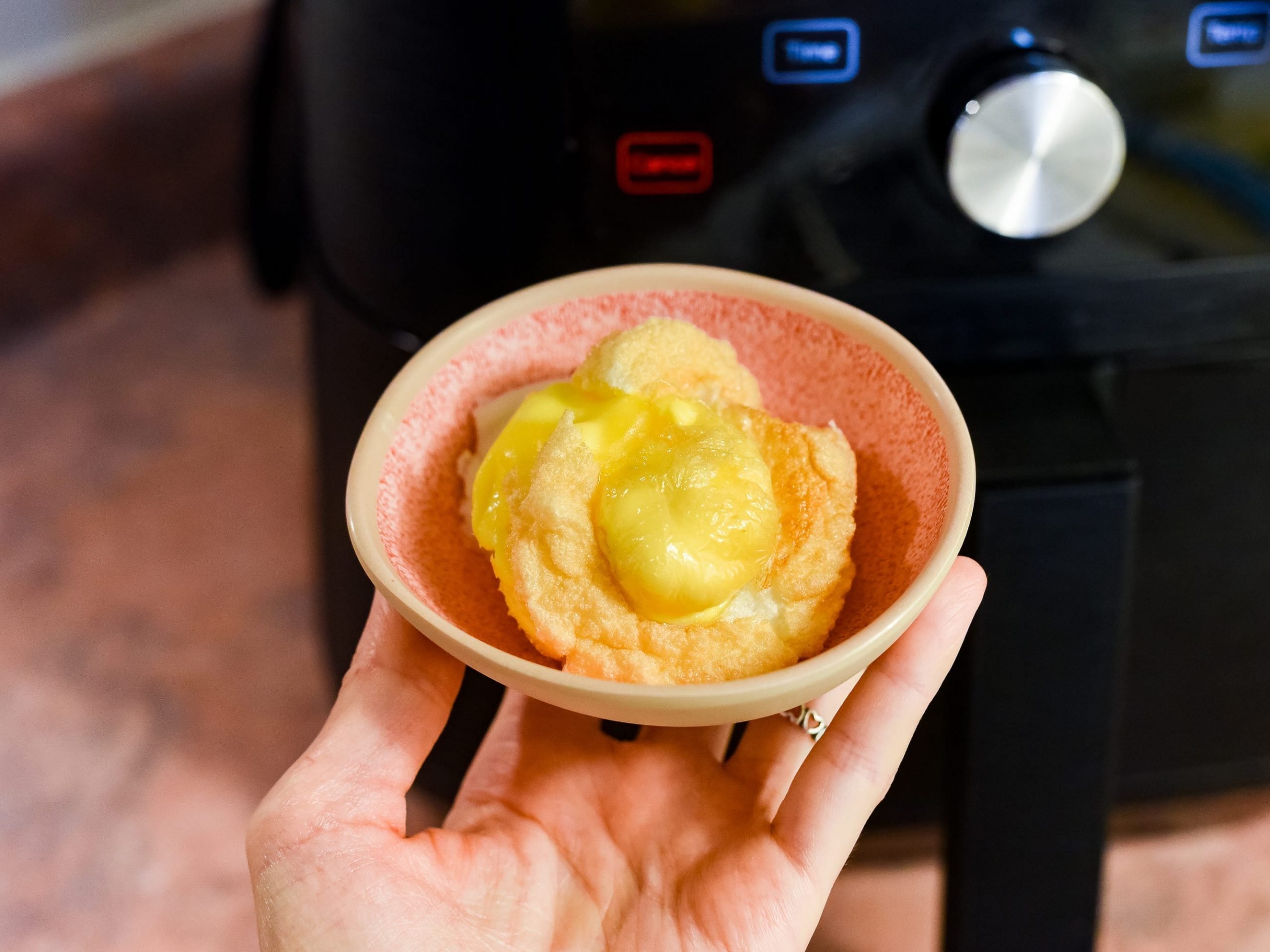 A hand holding up an air-fried egg.