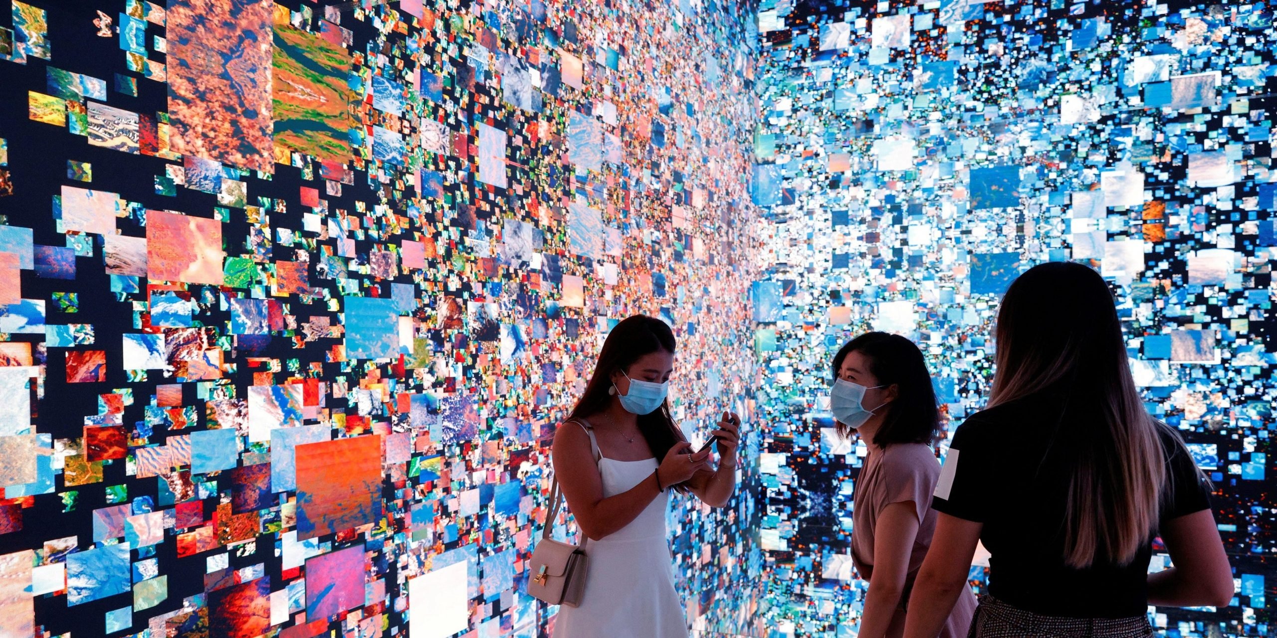 Visitors are pictured in front of an immersive art installation titled "Machine Hallucinations - Space: Metaverse" by media artist Refik Anadol, which will be converted into NFT and auctioned online at Sotheby's, at the Digital Art Fair, in Hong Kong, China September 30, 2021.