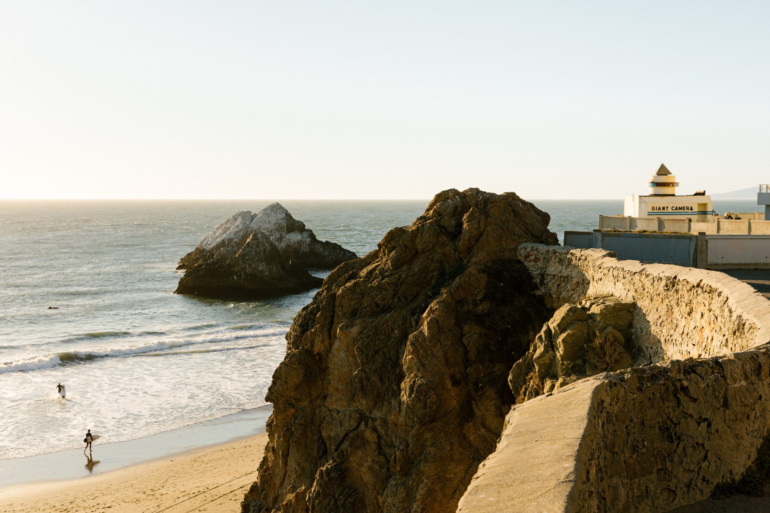 A shot of the ocean, surfers, and rock formations at Ocean Beach in San Francisco