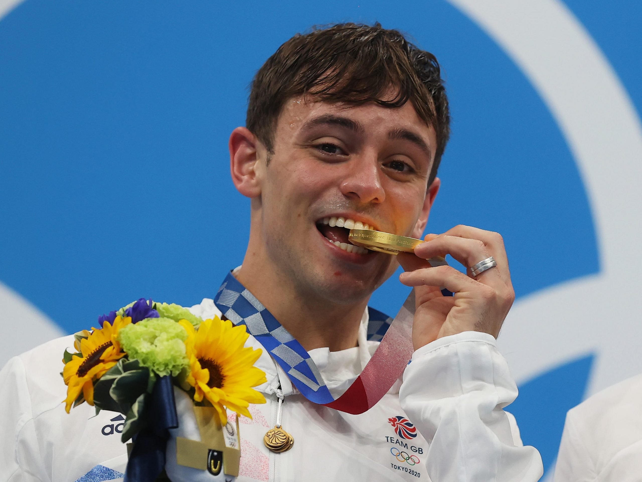 British diver Tom Daley biting his Tokyo Olympic gold medal