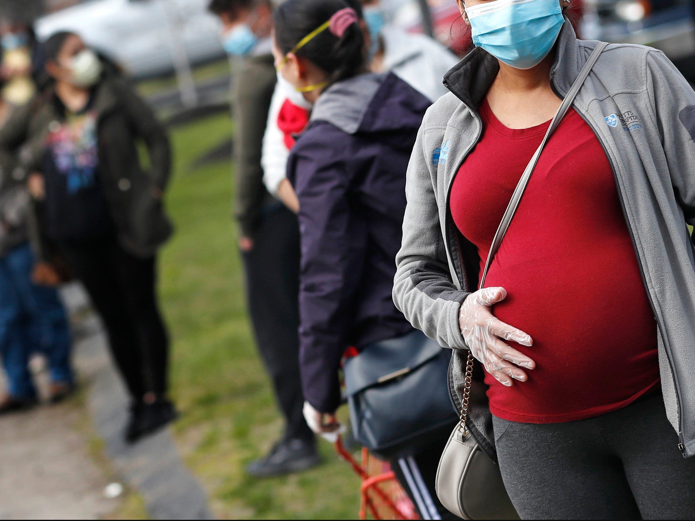 A pregnant woman wearing a face mask and gloves