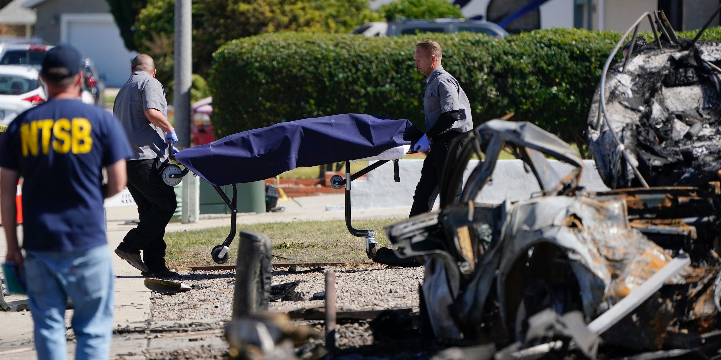 San Diego County medical examiner officials remove a gurney carrying remains from the site of the Santee plane crash