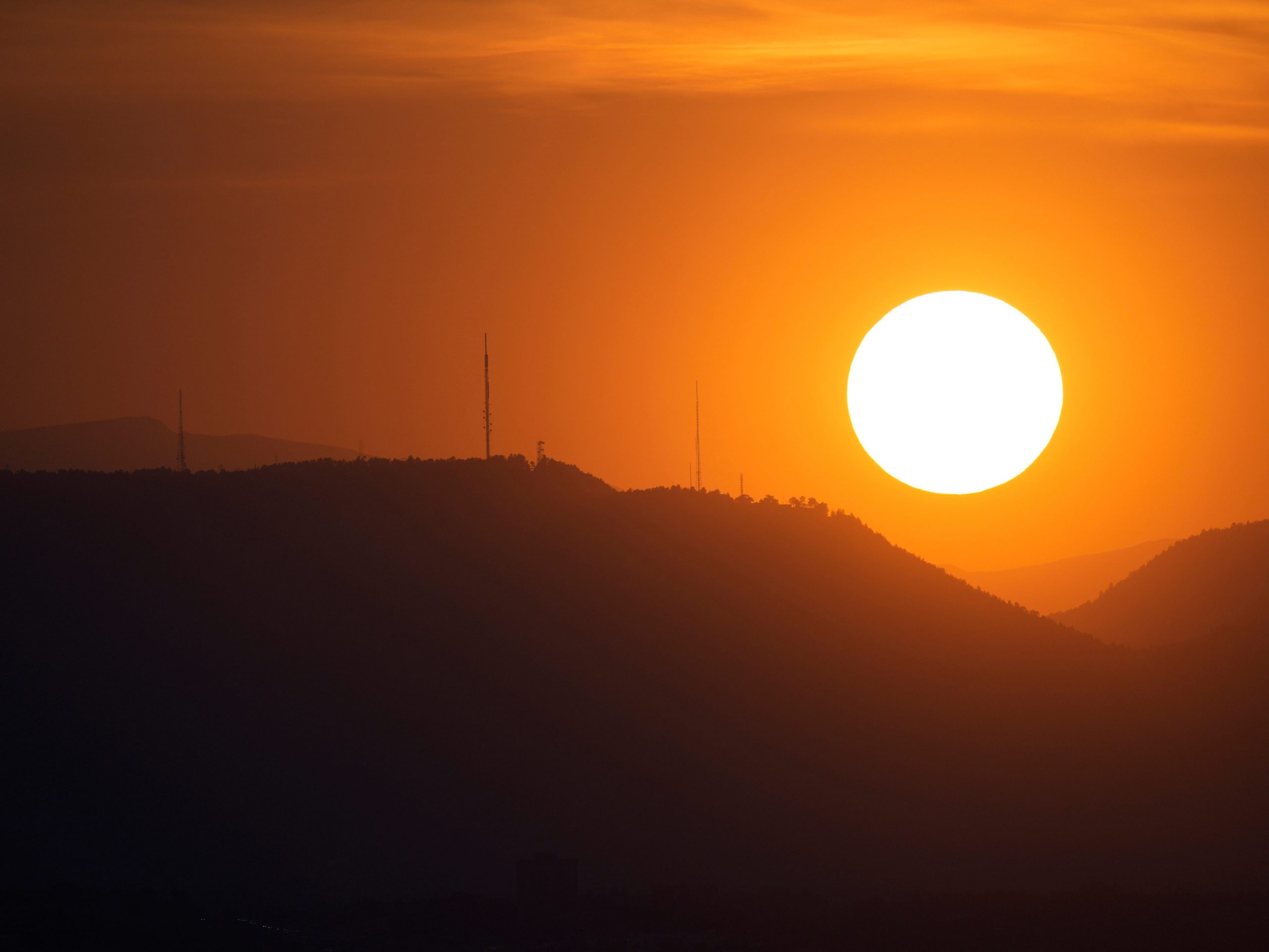 The sky is illuminated as the sun sets behind the Rocky Mountain Thursday, Sept. 10, 2021, in Denver.