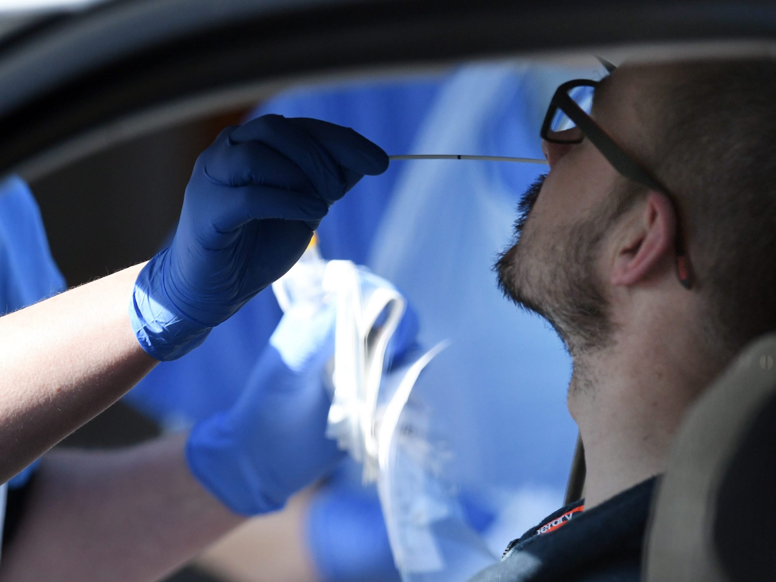 A medical staff member wearing PPE of gloves, eye protection, a face mask and an apron, tests an NHS worker for the novel coronavirus COVID-19 at a drive-in facility run by Wolverhampton NHS Clinical Commissioning Group, set up in a car park in Wolverhampton, central England on April 07, 2020.