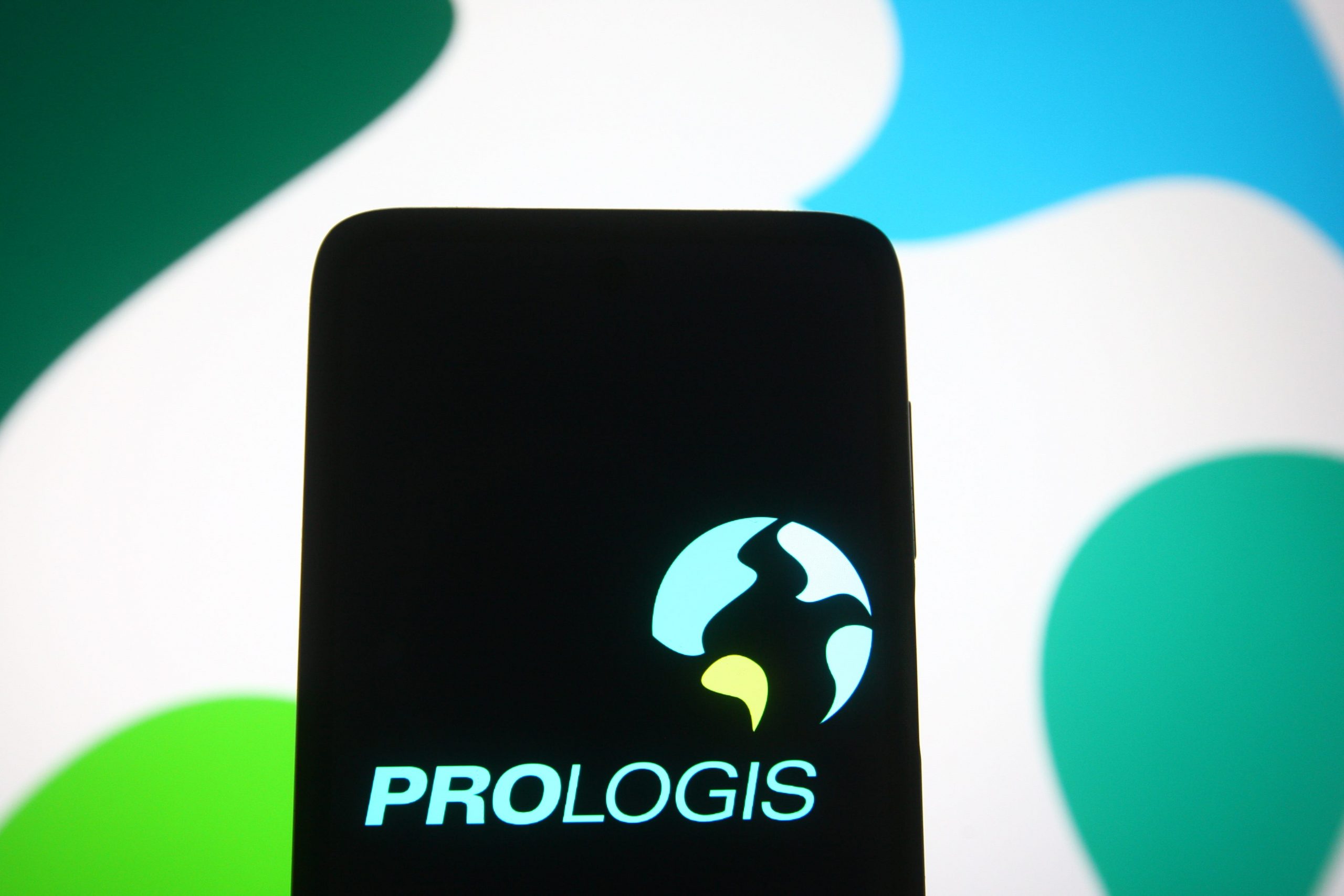 In this photo illustration, Prologis logo of a real estate investment trust company is seen on a smartphone and a pc screen.