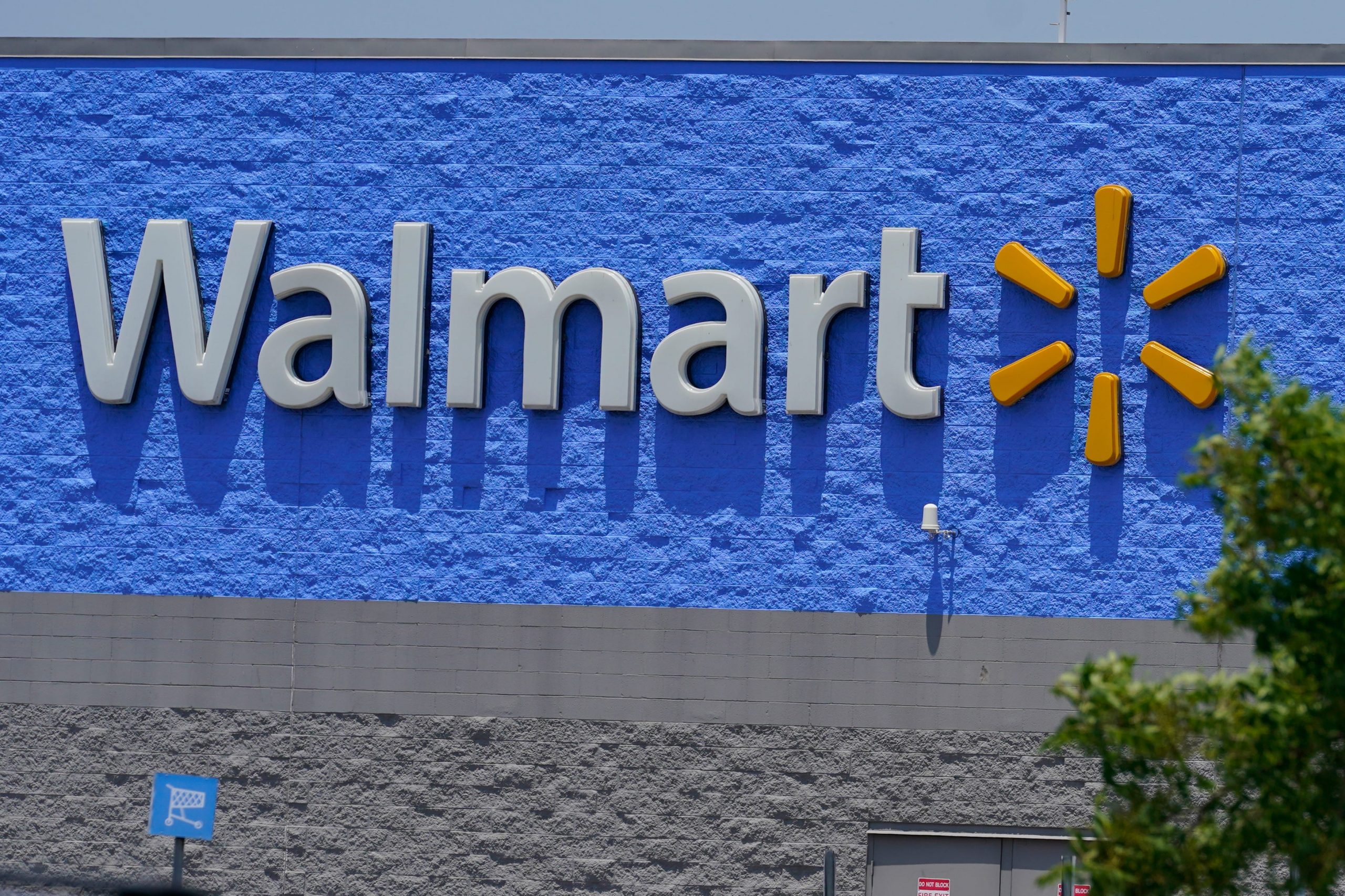 A Walmart sign on a blue painted wall on a sunny day
