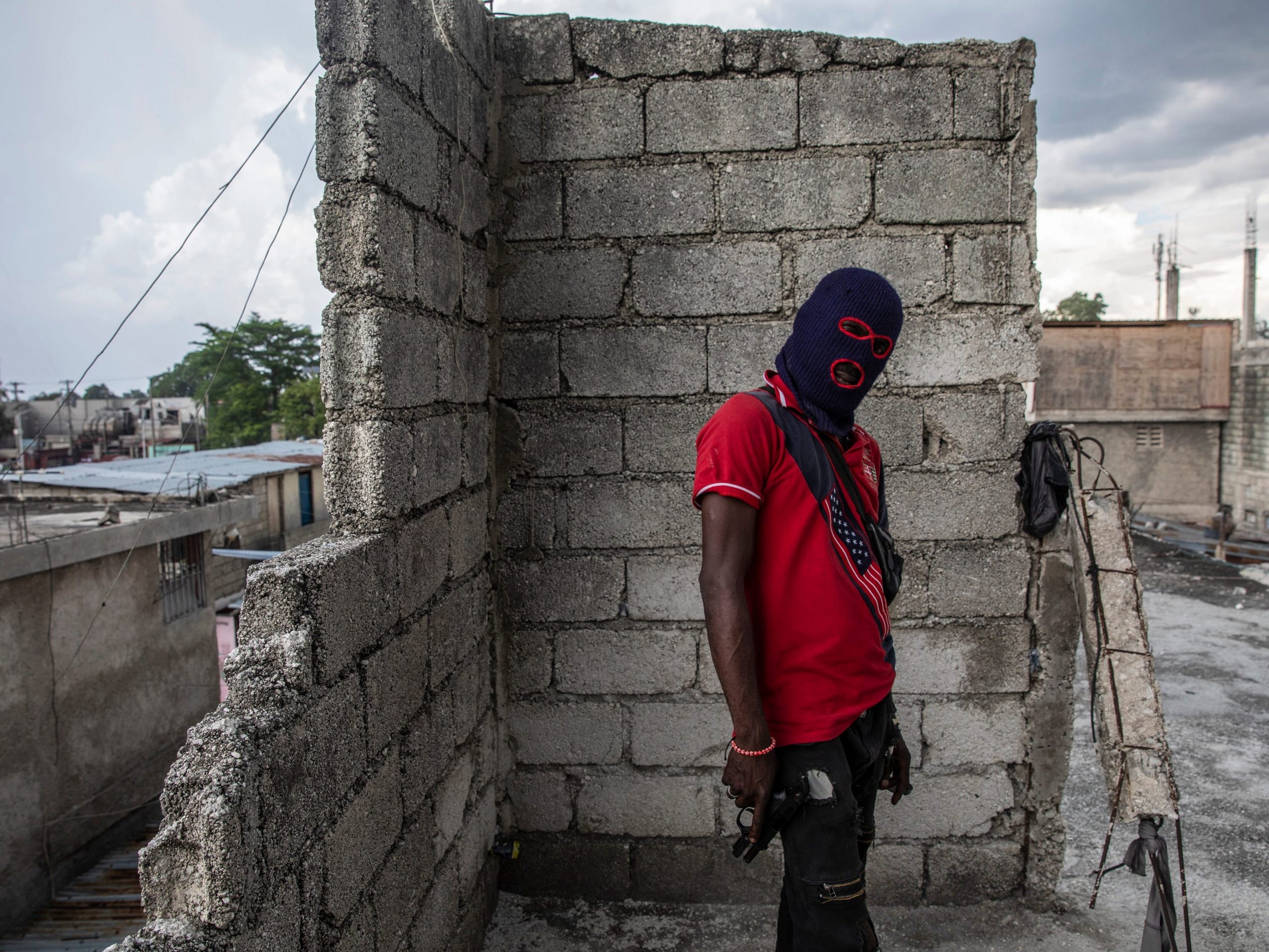 A gang member, wearing a balaclava and holding a gun, poses for a photo in the Portail Leogane neighborhood of Port-au-Prince, Haiti