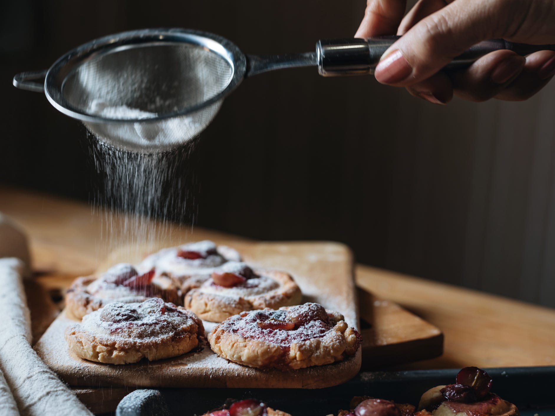 Powdered sugar being sprinkled over some cookies.