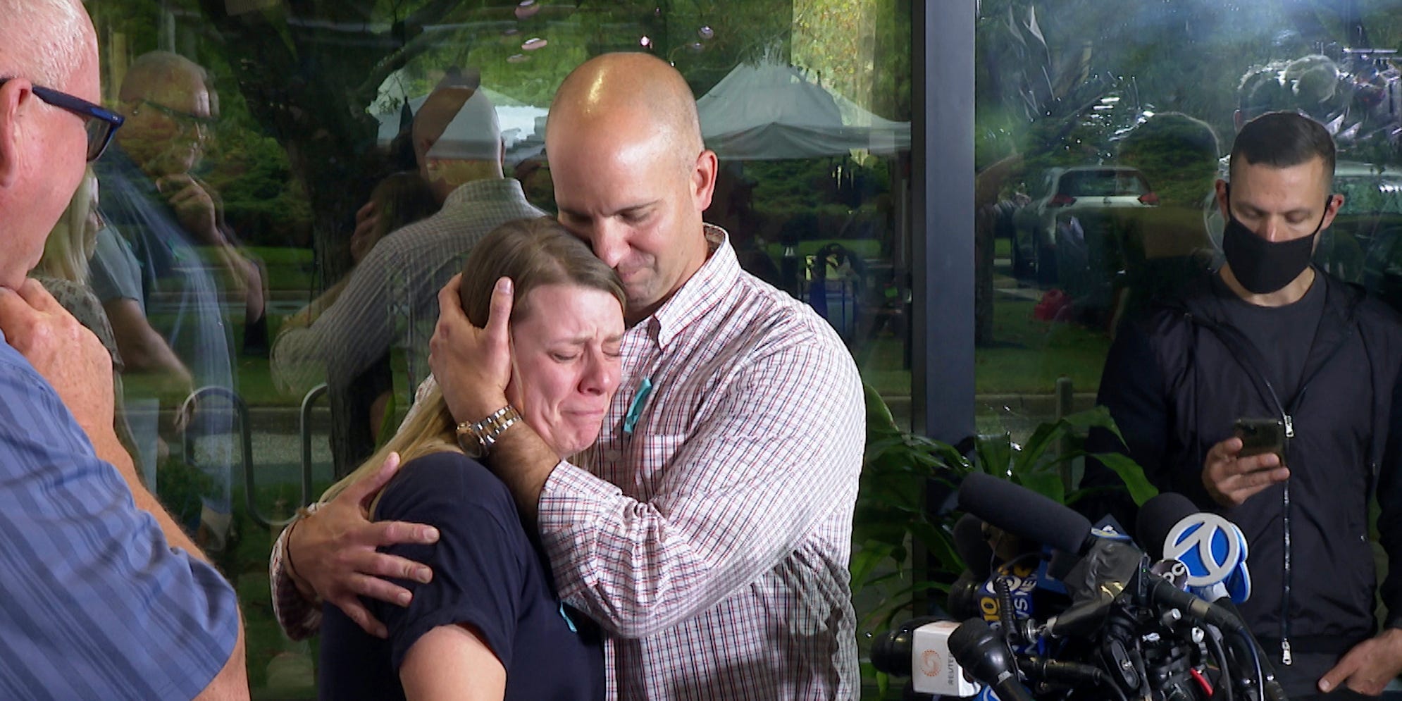 Jim Petito cradles a distraught-looking Nichole Schmidt in front of onlookers and microphones at a press conference about Gabby Petito.