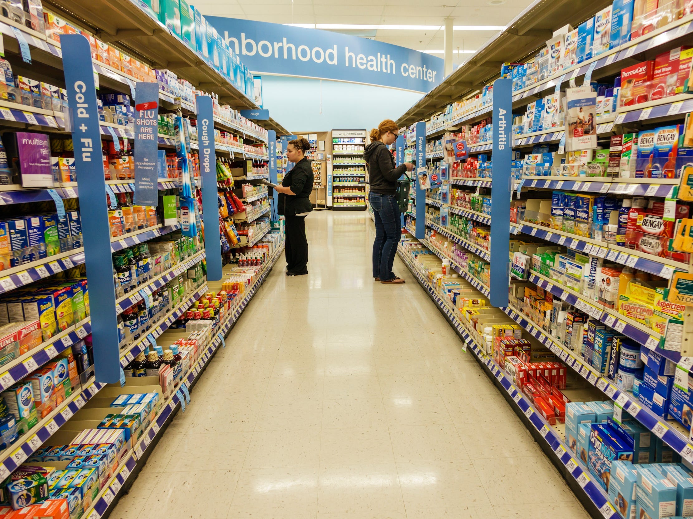 Two women shop for cold and flu medicine in aisle of Walgreens store