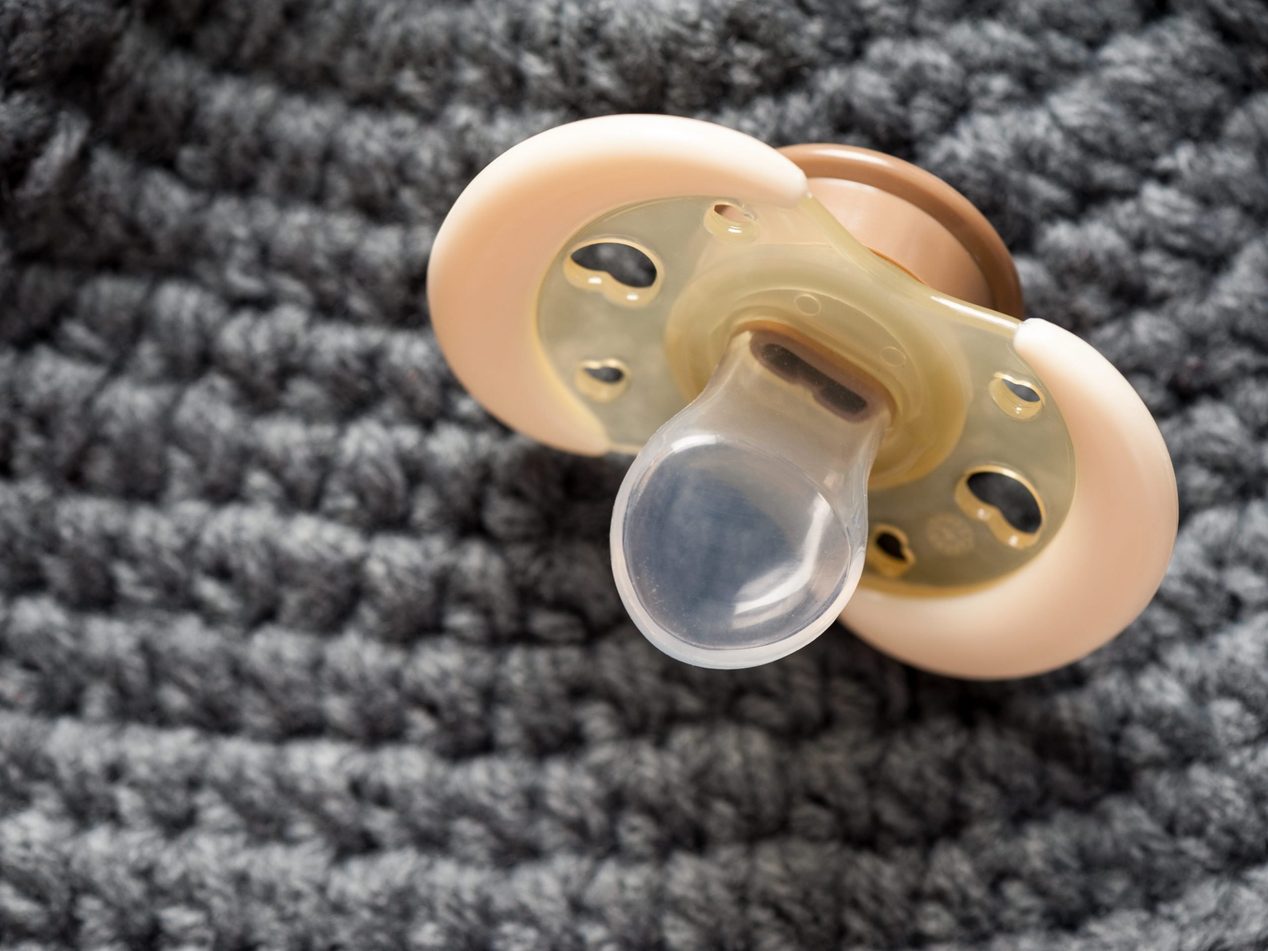 baby pacifier sitting on a gray knit blanket