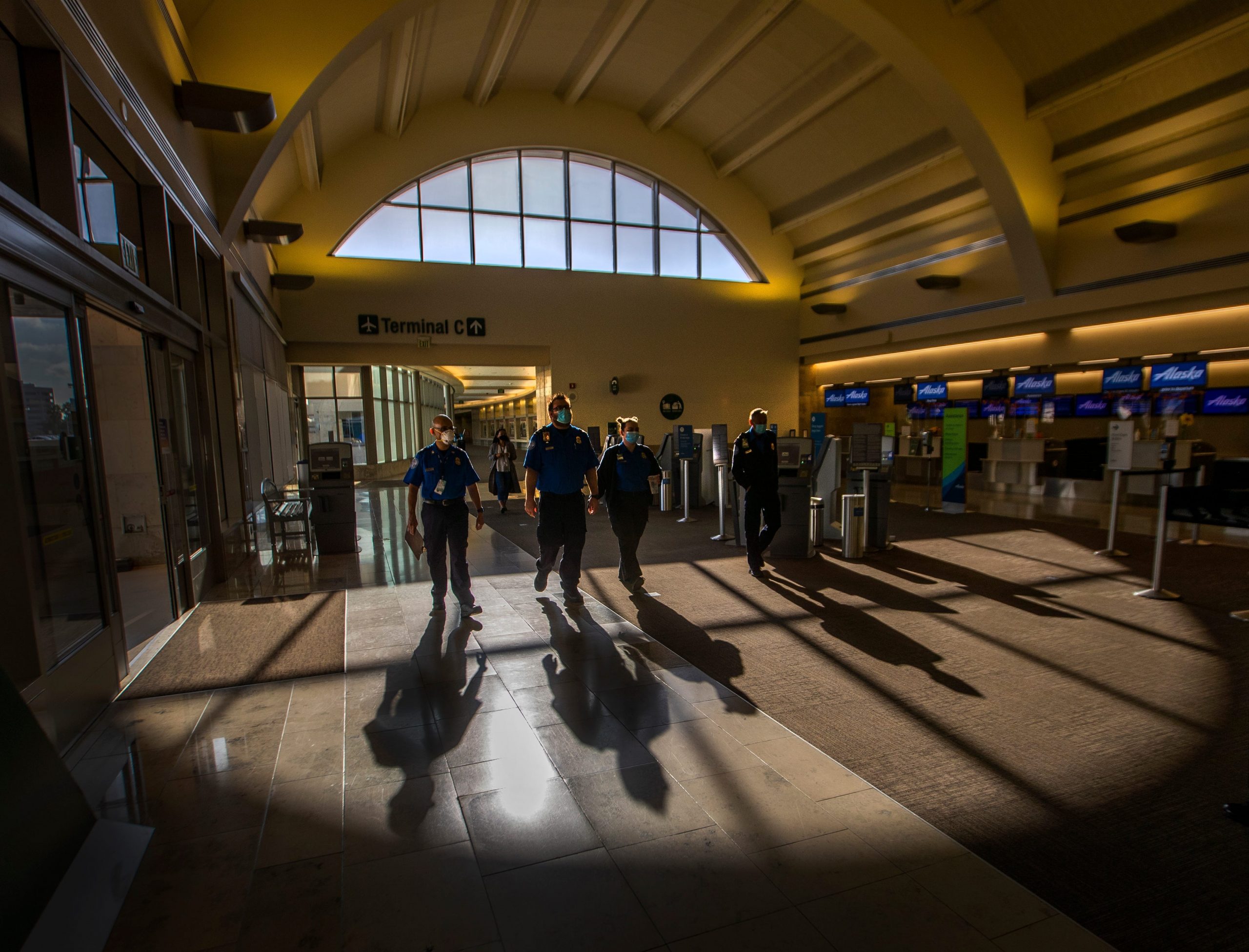 A group of TSA agents in masks walk through John Wayne Airport in California