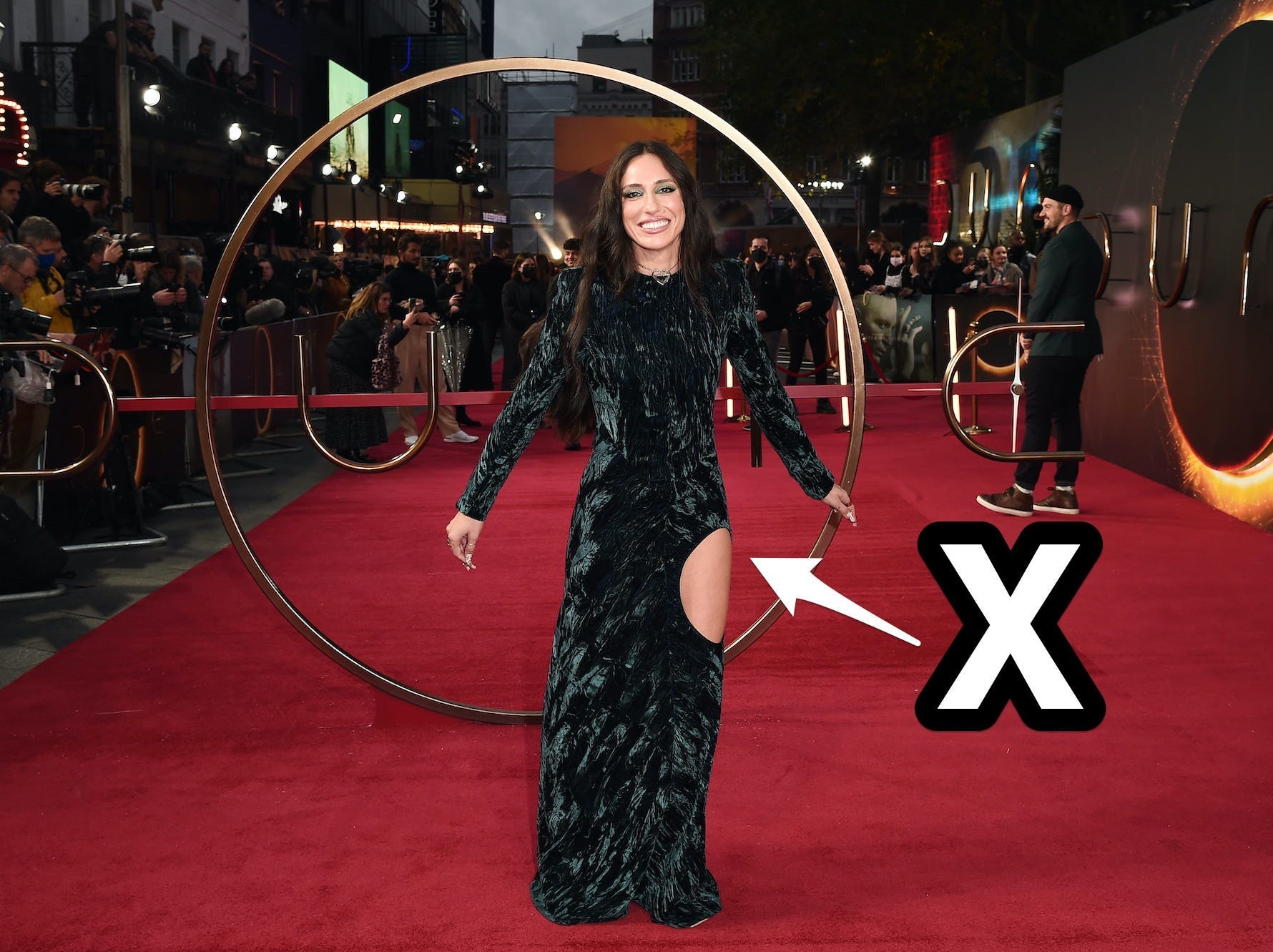 A photo of Tefi Pessoa smiling on the "Dune" red carpet with an arrow and an X pointing to her dress.