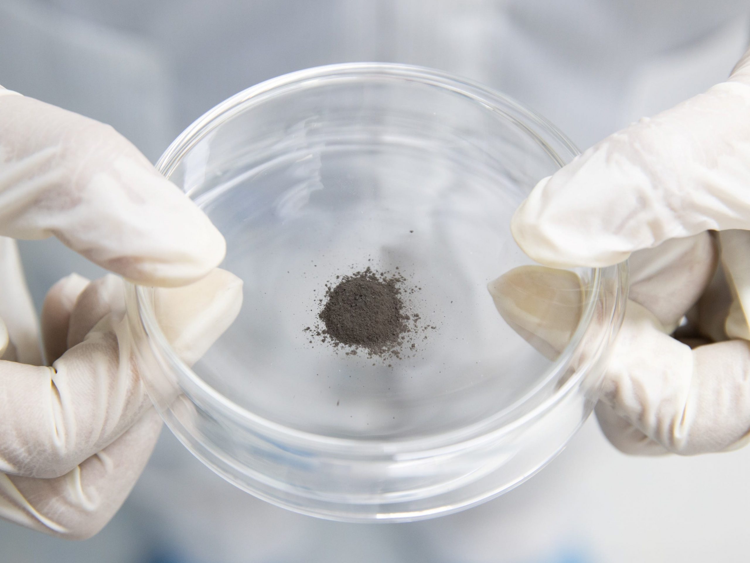 china moon samples gloved hands holding dirt dust in a clear dish