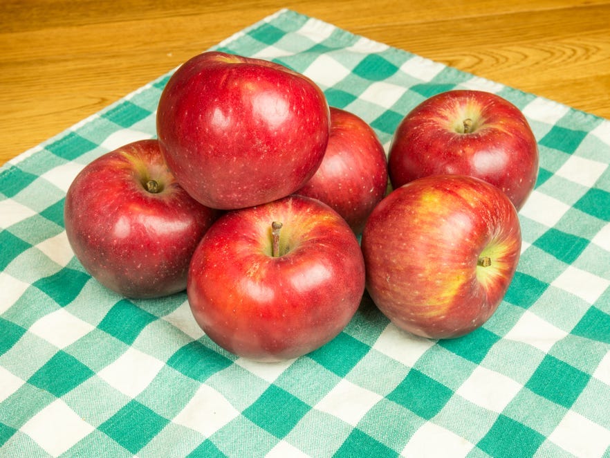 Six Winesap apples on a checkered cloth.