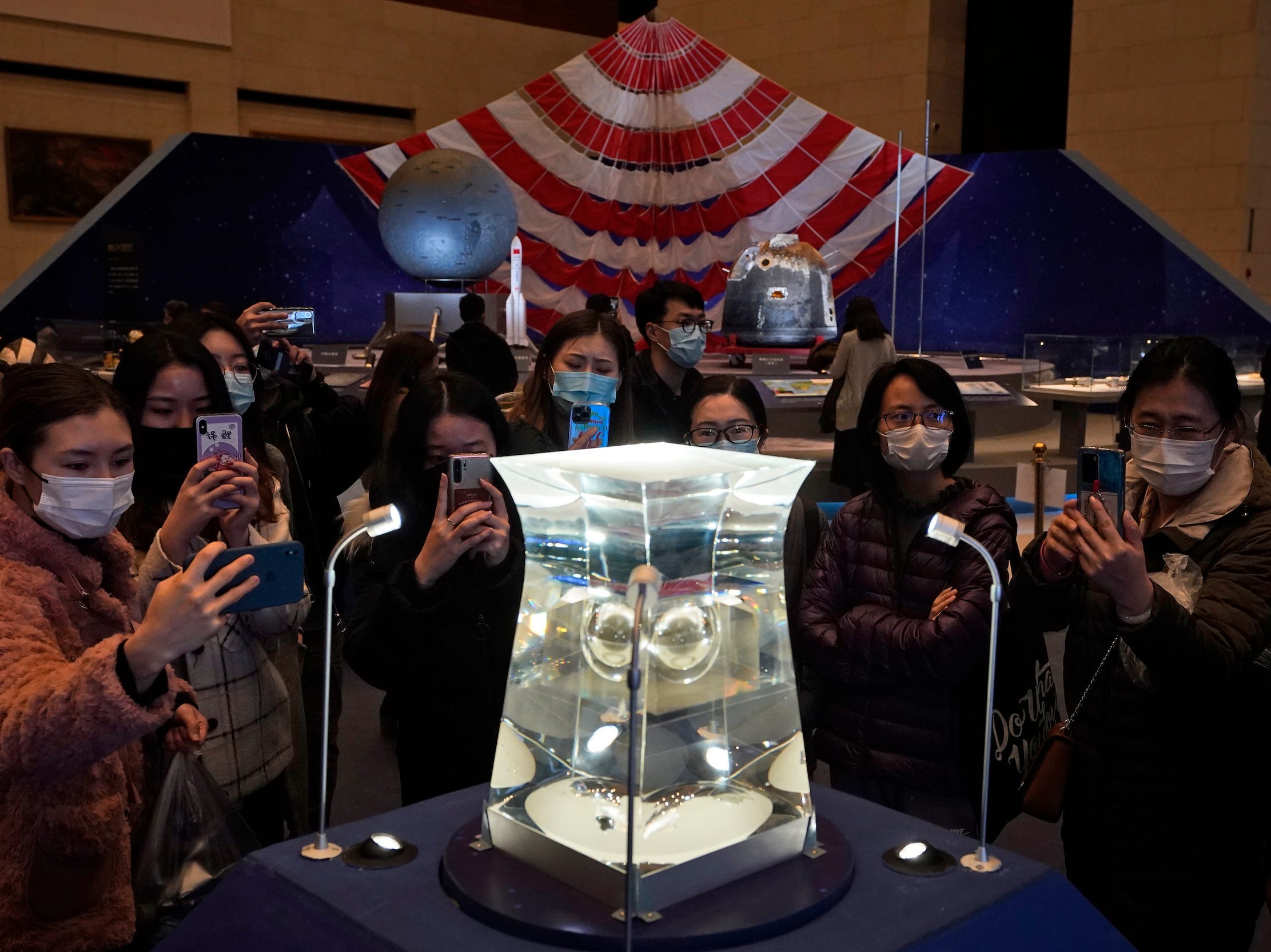 crowd takes pictures of moon samples in glass case