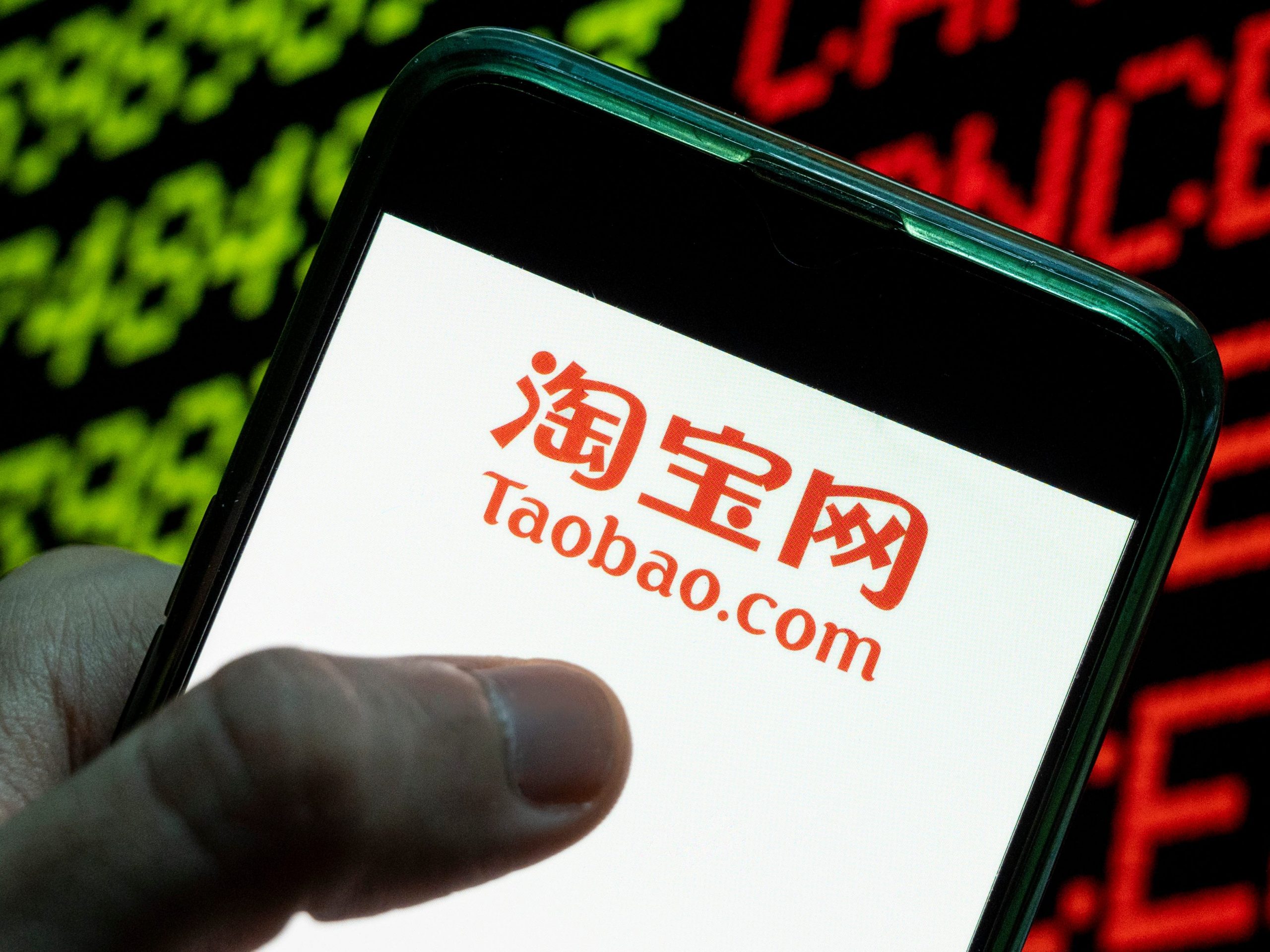 In this photo illustration the Chinese online shopping website owned by Alibaba Group, Taobao logo seen displayed on a smartphone with the word cancelled on a computer screen.