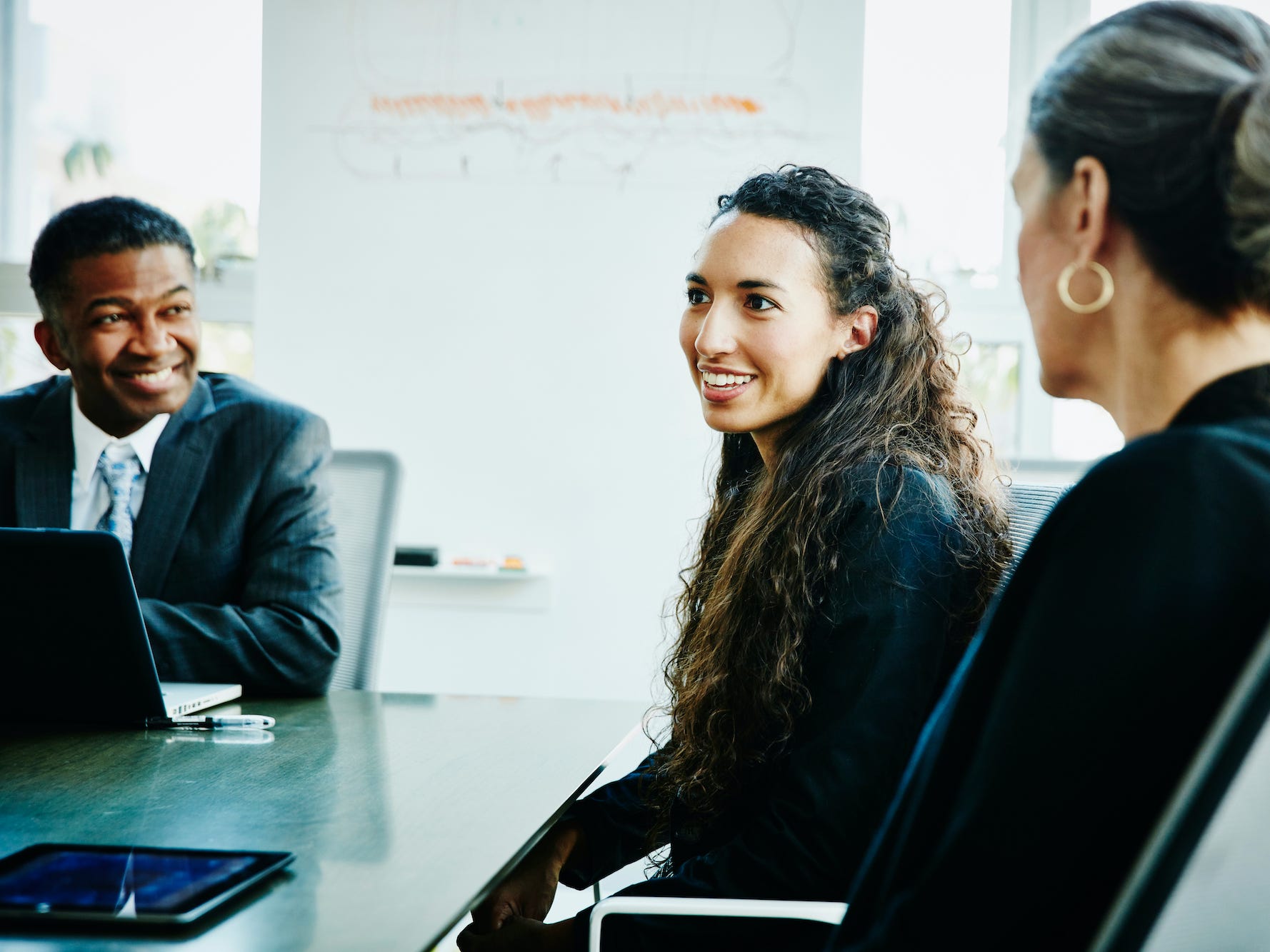 Smiling businesswoman leading discussion during meeting in office conference room