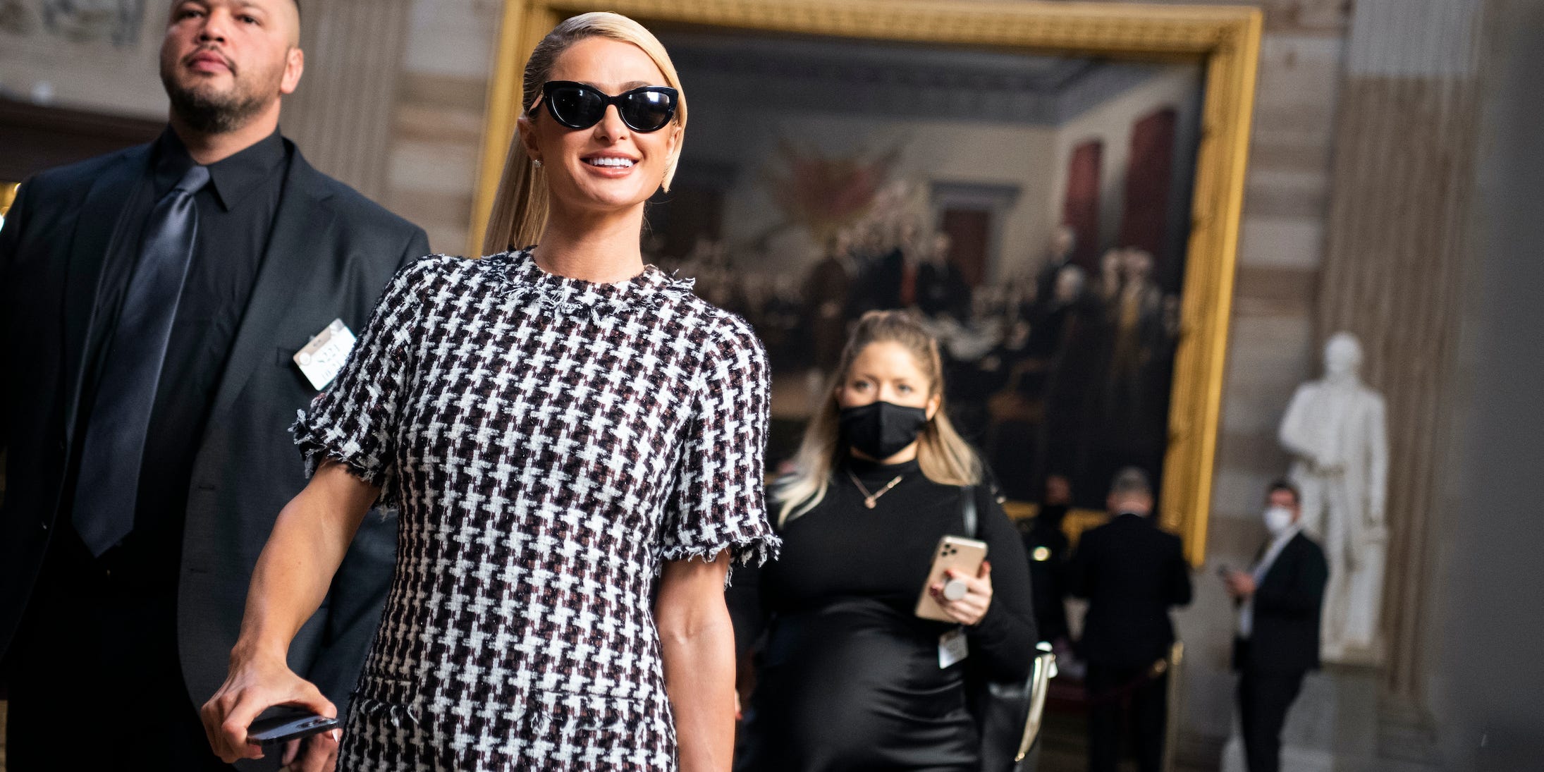 Paris Hilton walks through the Capitol rotunda in a black and white checkered dress.