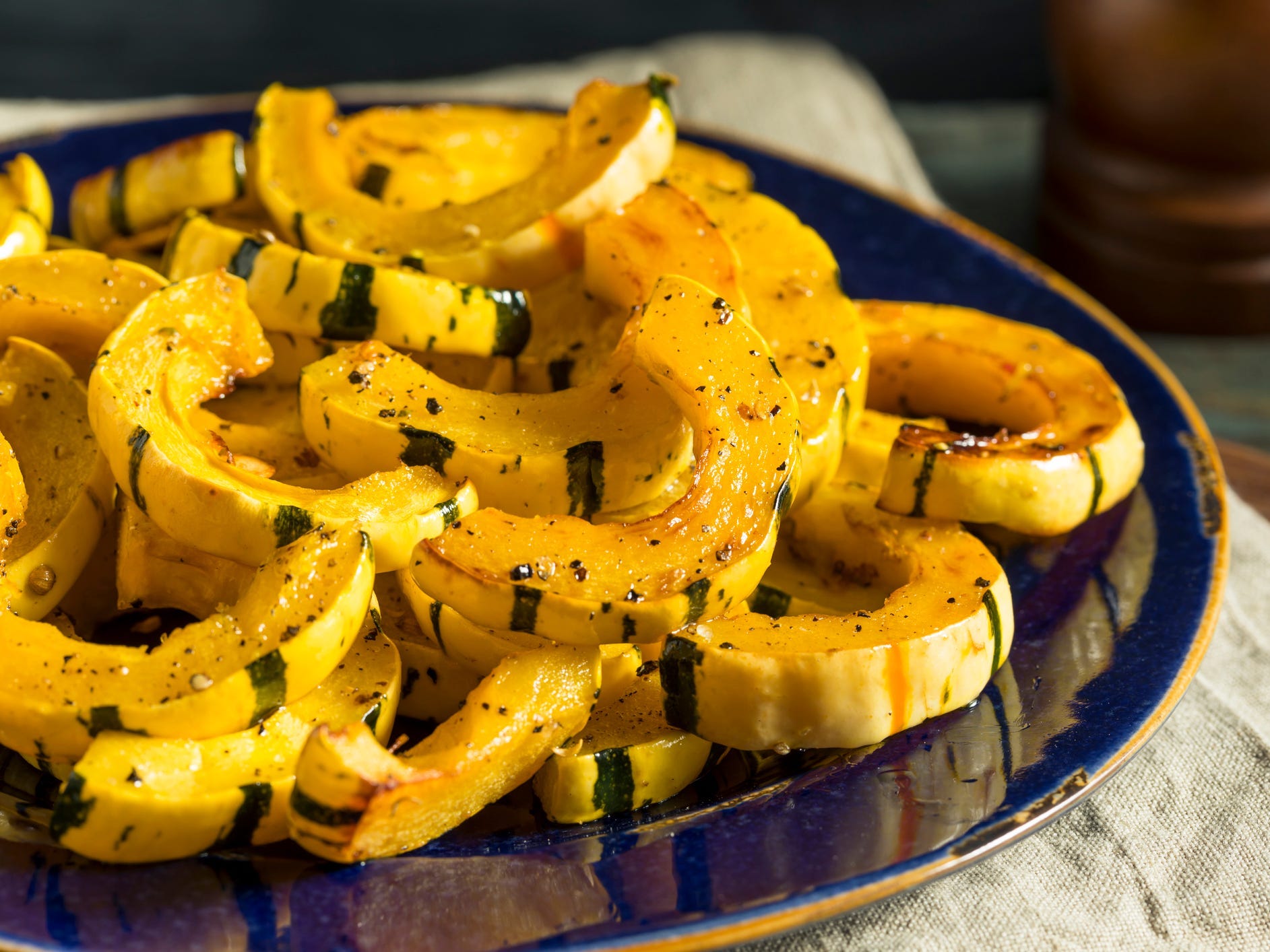 Half-rings of roasted delicata squash on a blue plate