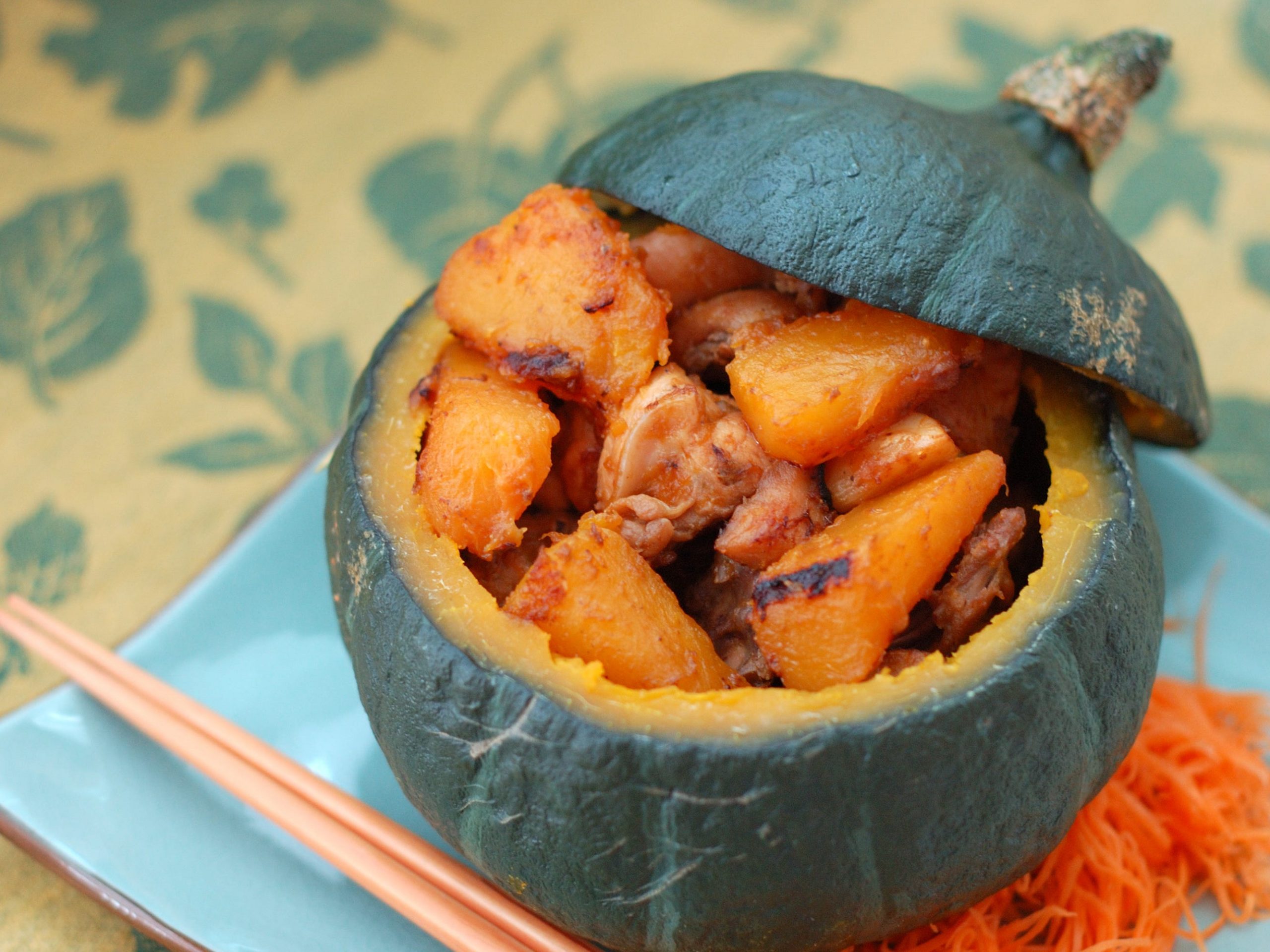 A kobocha squash with the top cut off that's been roasted and stuffed with squash and chicken