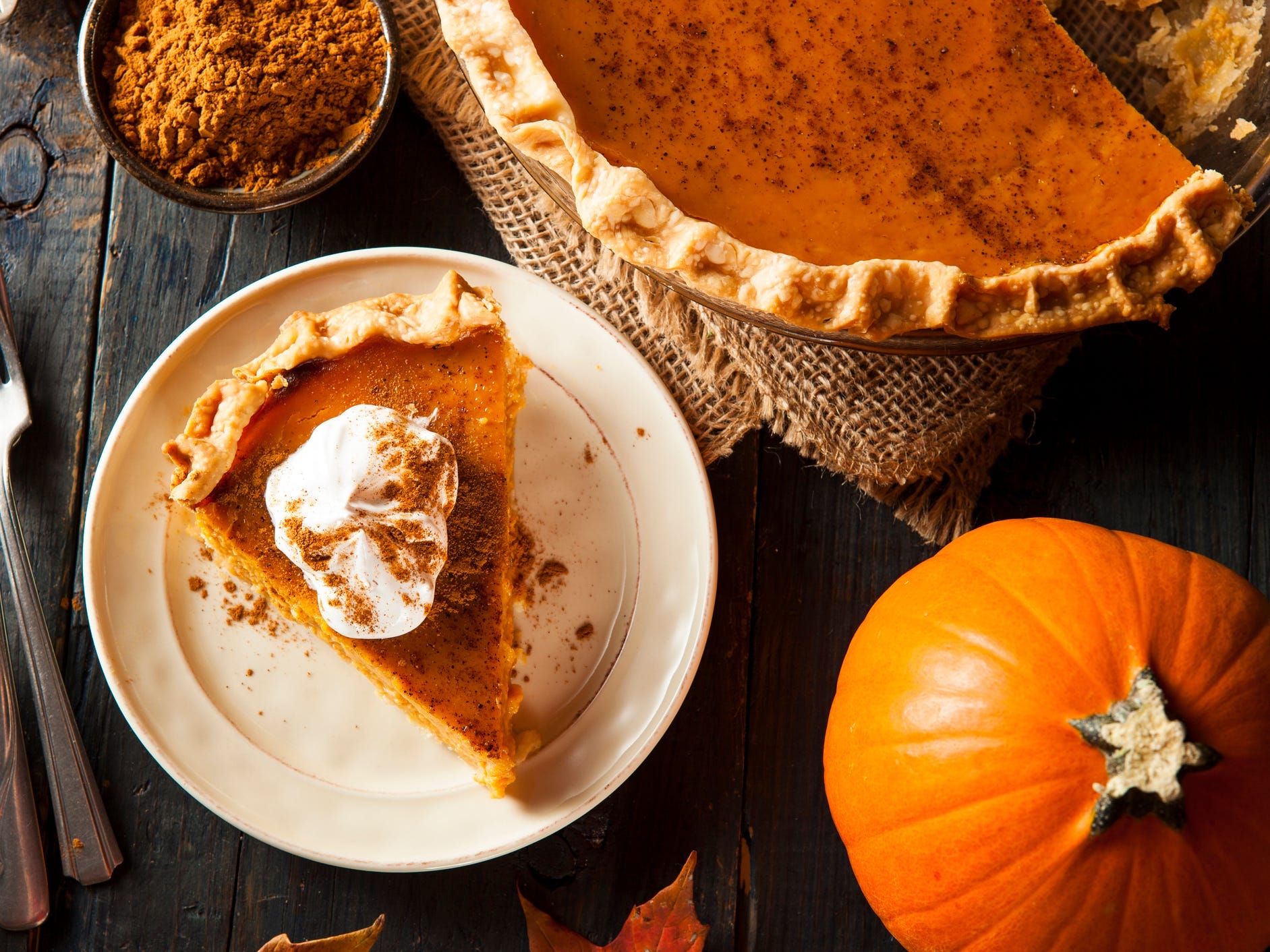 A slice of pumpkin pie on a plate topped with whipped cream