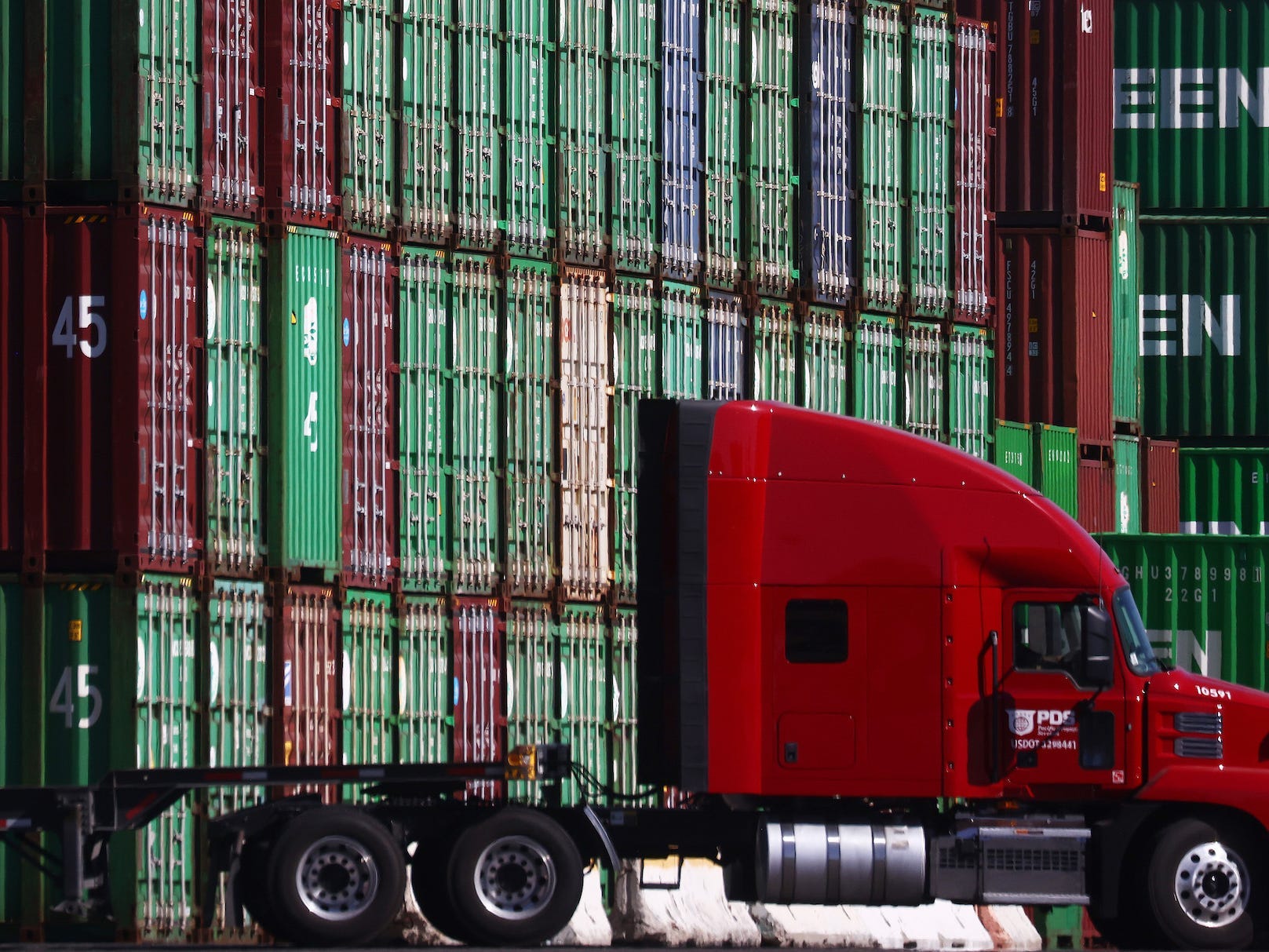 A truck drives past cargo containers stacked at the Port of Los Angeles, the nation’s busiest container port, on October 15, 2021 in San Pedro, California.