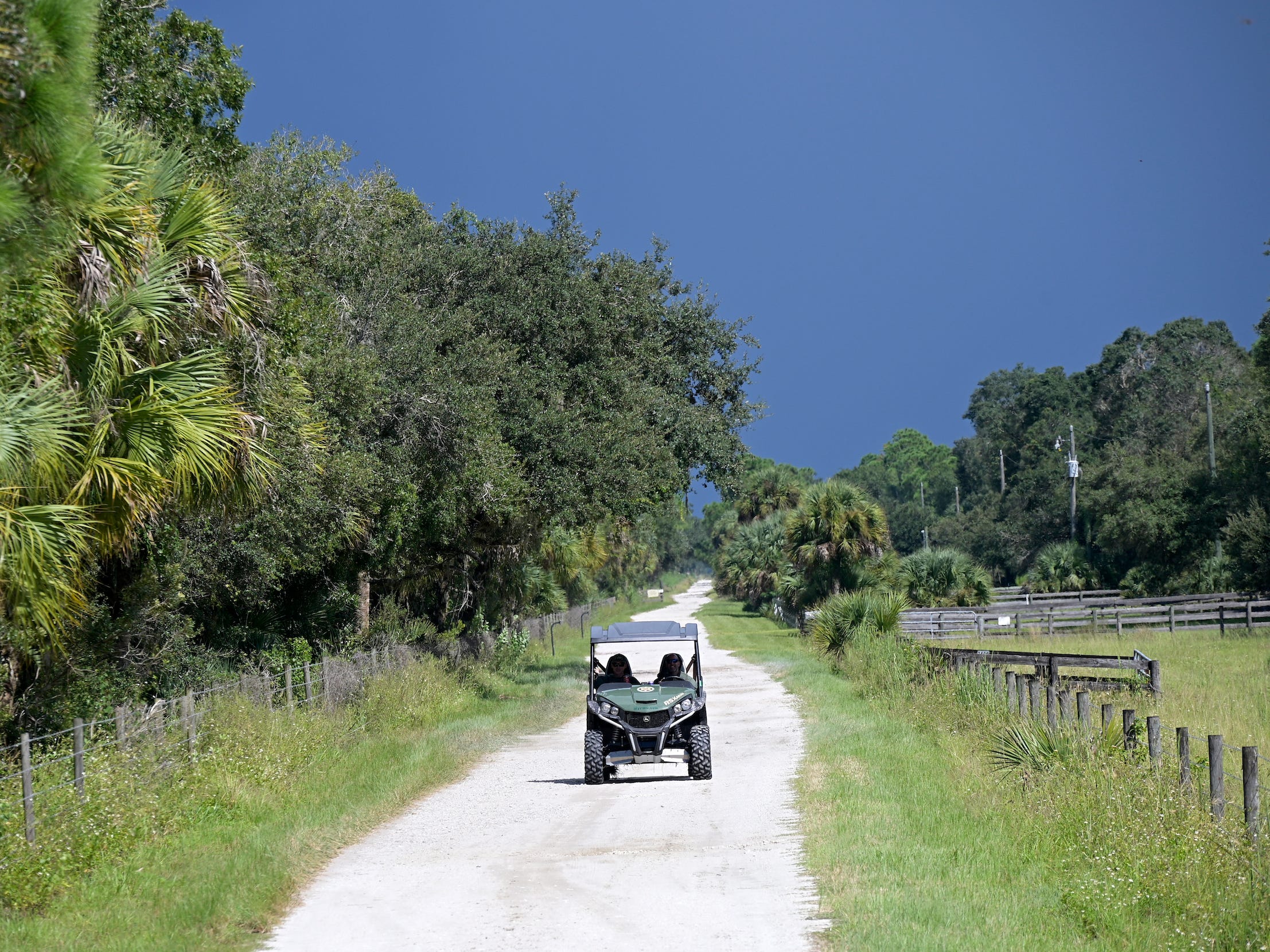 in the Carlton Reserve, a side-by-side vehicle drives along a path with trees alongside it and a stormy sky