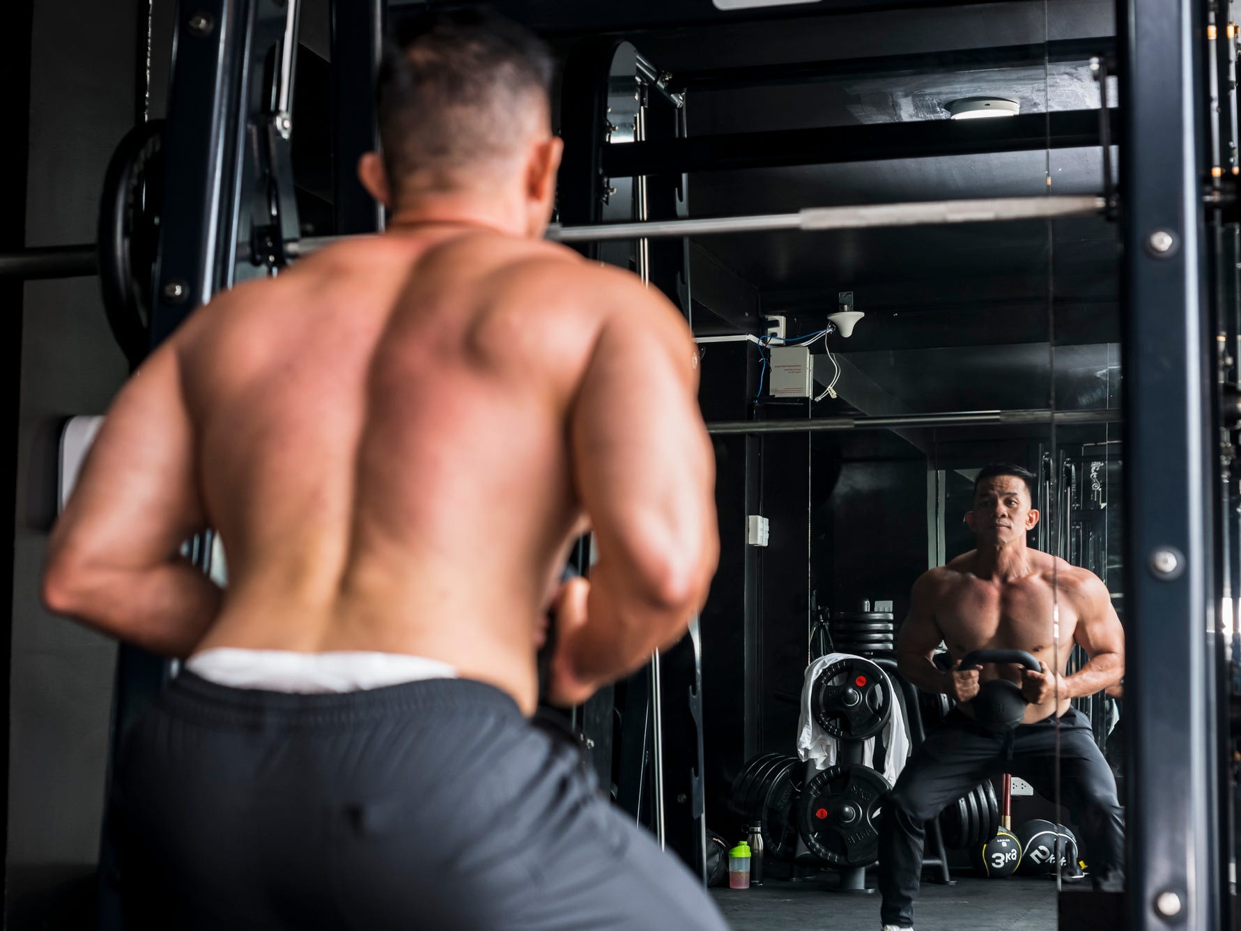 an athlete performing a goblet squat with a kettlebell in a gym mirror