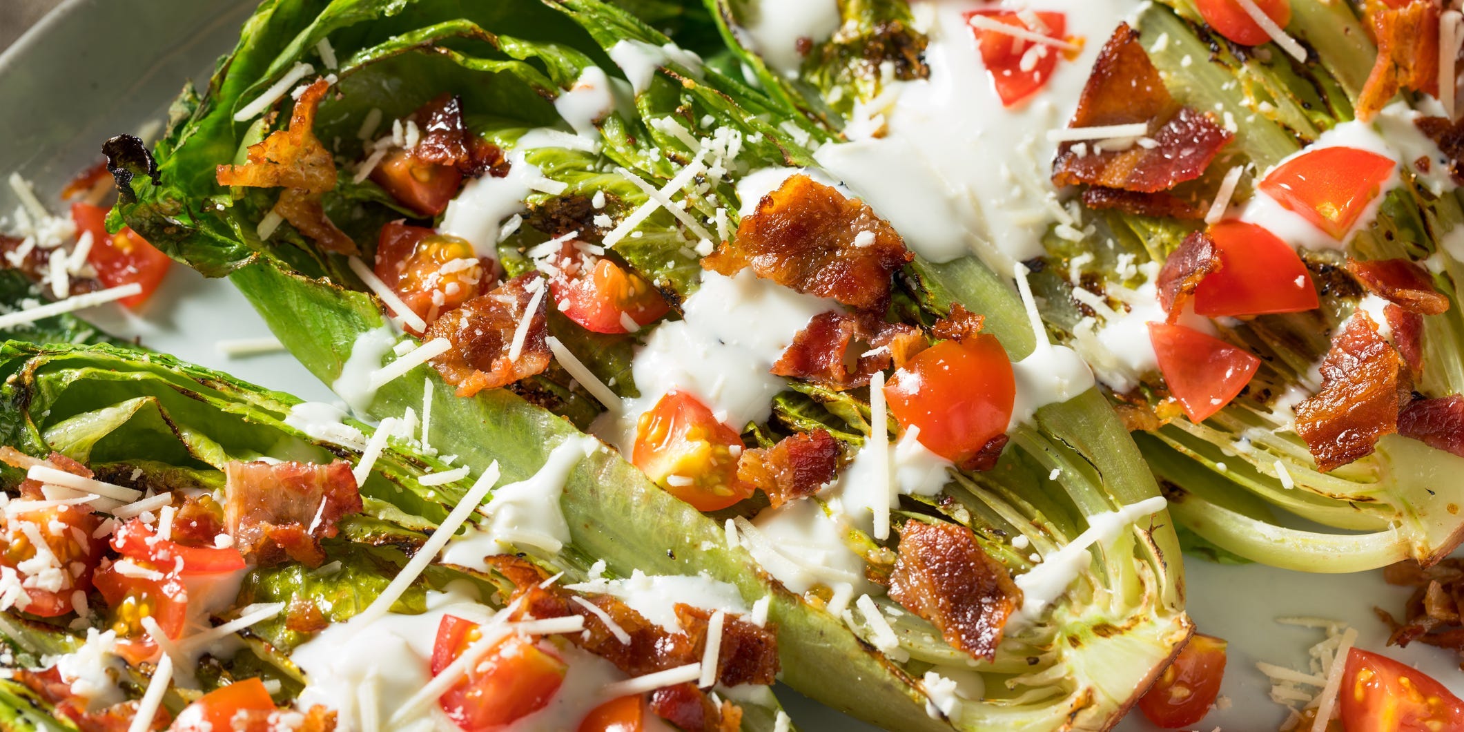 Grilled romaine lettuce topped with bacon, tomatoes, and blue cheese dressing