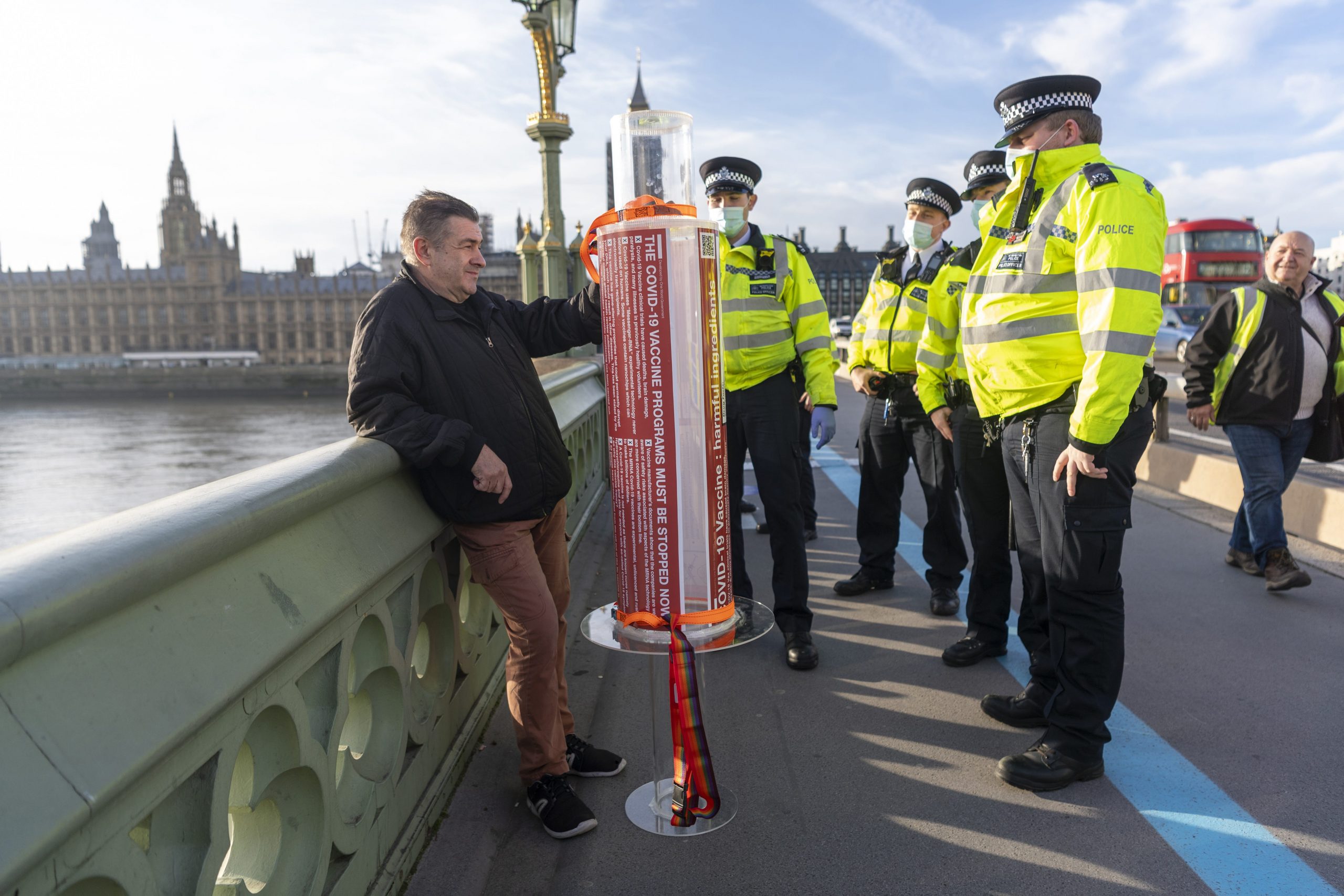 A protester with a model Covid 19 vaccine syringe is detained by police officers at a demonstration against a COVID-19 vaccine education event in London, United Kingdom on November 24, 2020