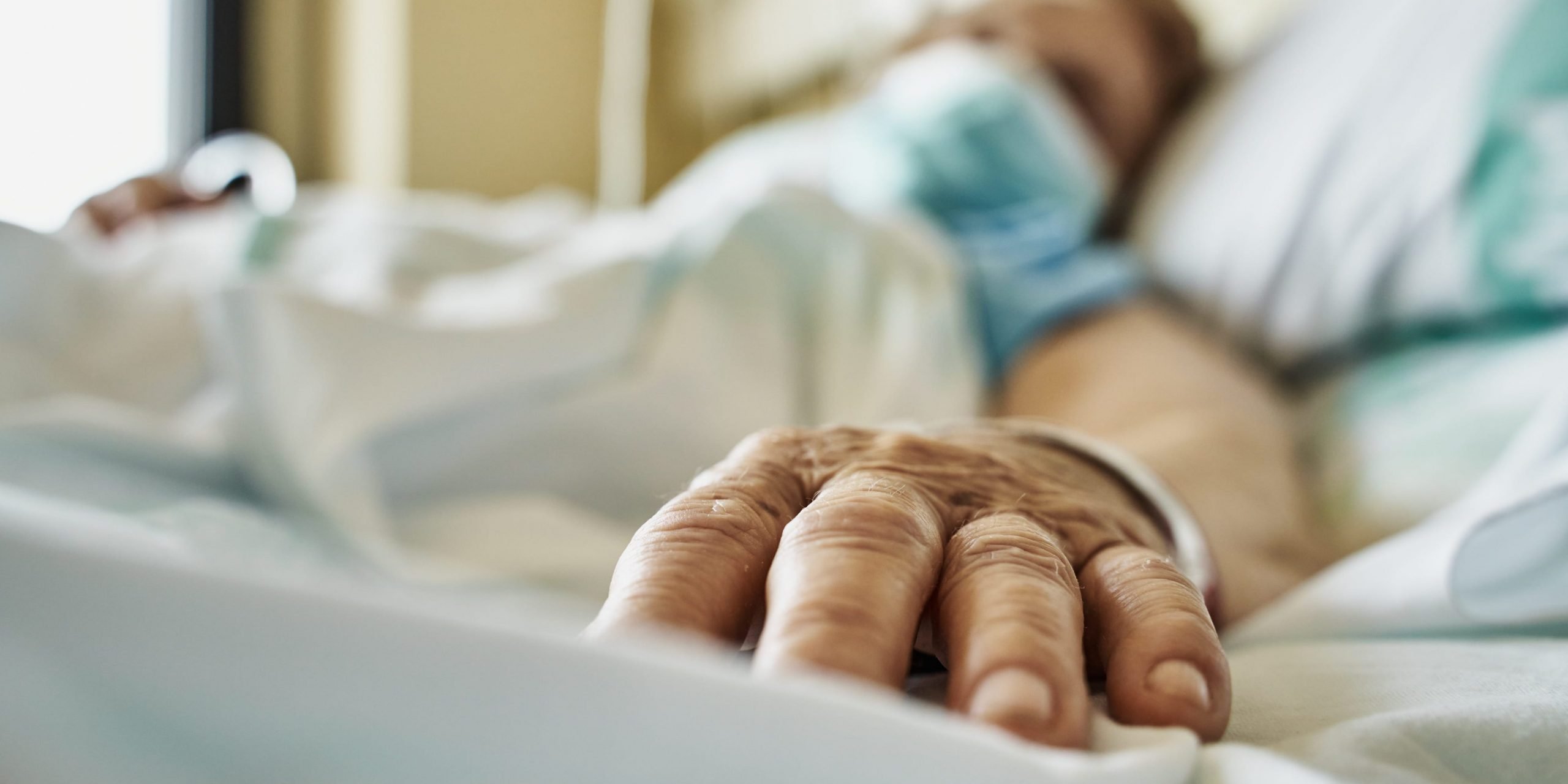 Patient on hospital bed receiving medicine by drip.