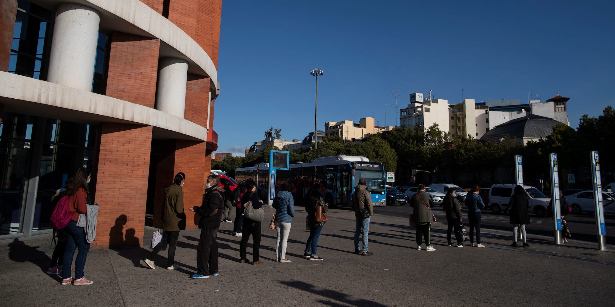 People wearing face masks to prevent the spread of coronavirus queue for a bus during a partial lockdown in downtown Madrid, Spain, Monday, Oct. 5, 2020.