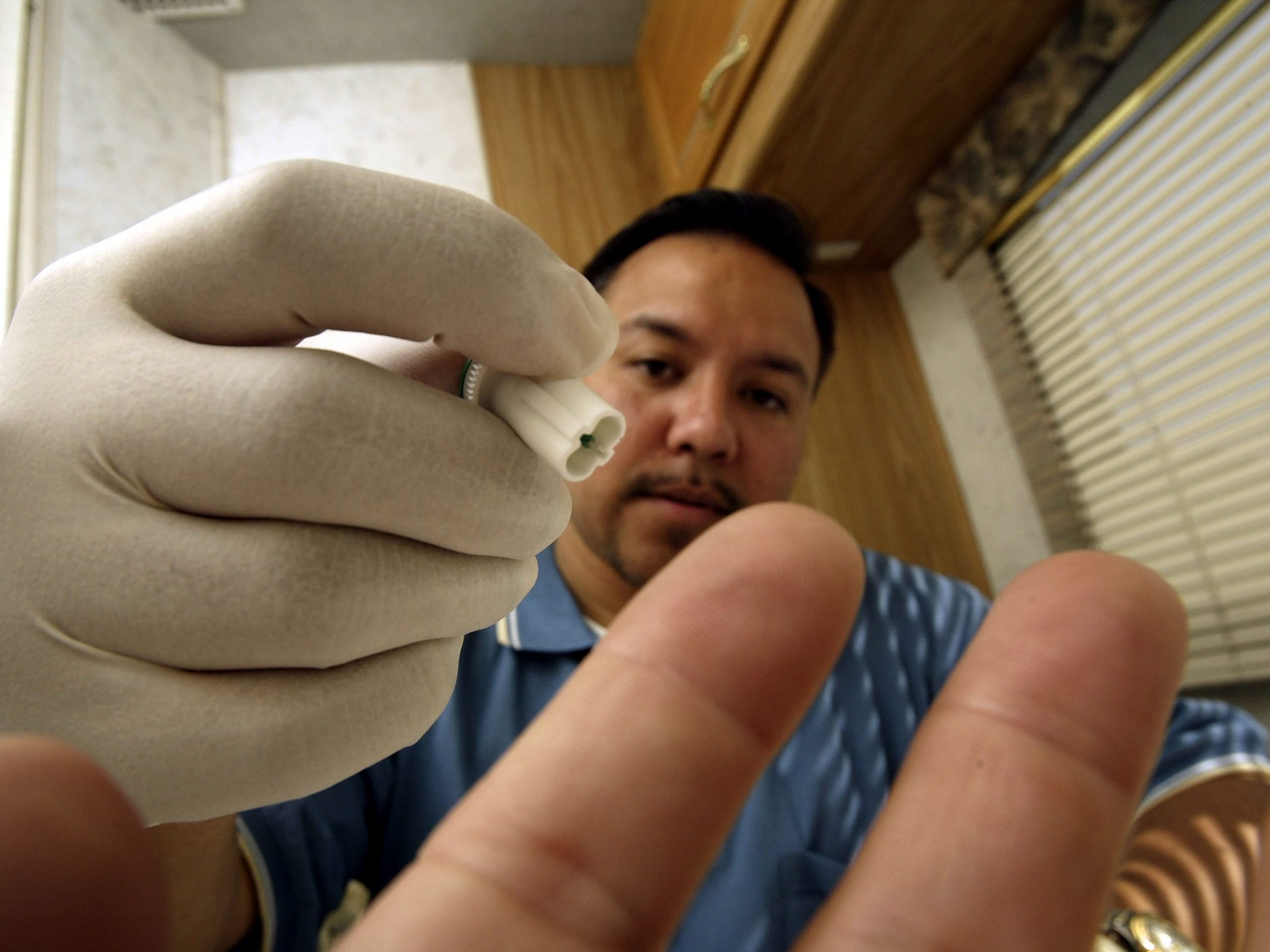 Joe Mendoza, AIDS Healthcare Foundation (AHF) mobile testing program manager, uses the photographer's finger to demonstrate how a lancet from the OraQuick Rapid HIV-1 Antibody Test kit would be used to obtain a blood sample inside the AHF mobile HIV screening lab on its first day of operations April 28, 2004 in Los Angeles, California.