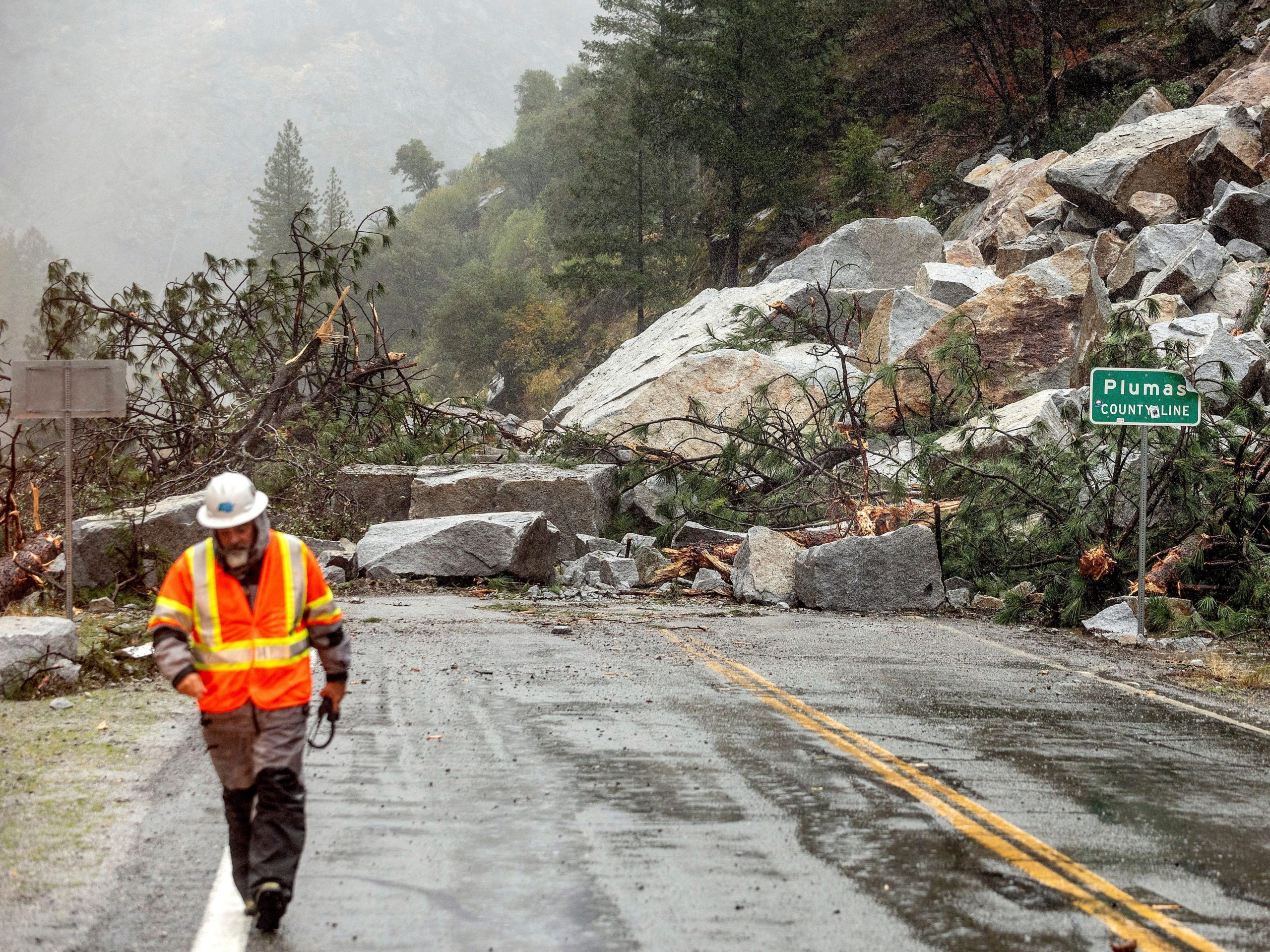 Caltrans maintenance supervisor Matt Martin walks by a landslide covering Highway 70 in the Dixie Fire zone on Sunday, Oct. 24, 2021, in Plumas County, Calif.