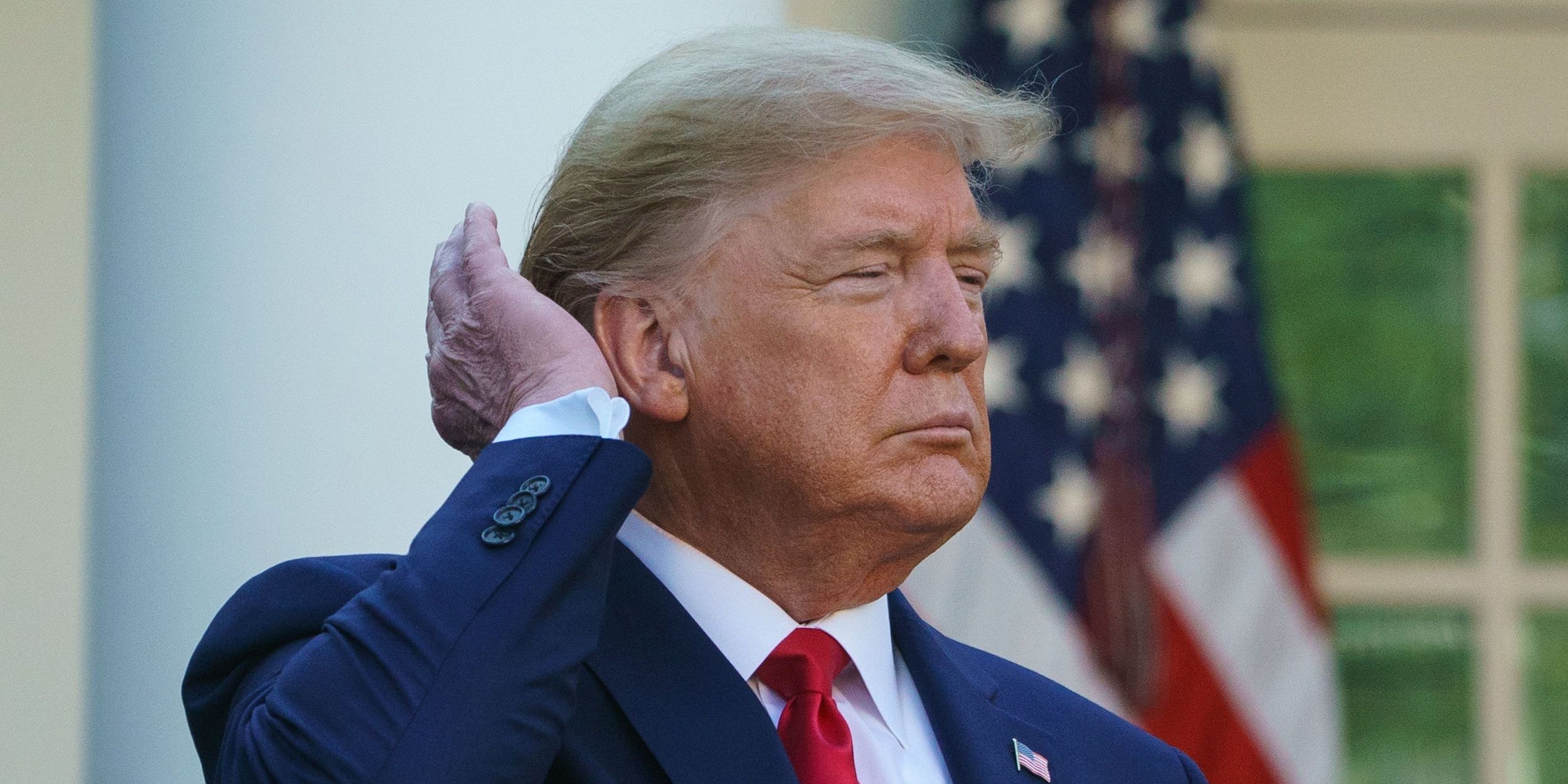 Donald Trump pats down his hair as he speaks during the Coronavirus Task Force daily briefing on COVID-19 in the Rose Garden of the White House in Washington, DC on March 30, 2020.