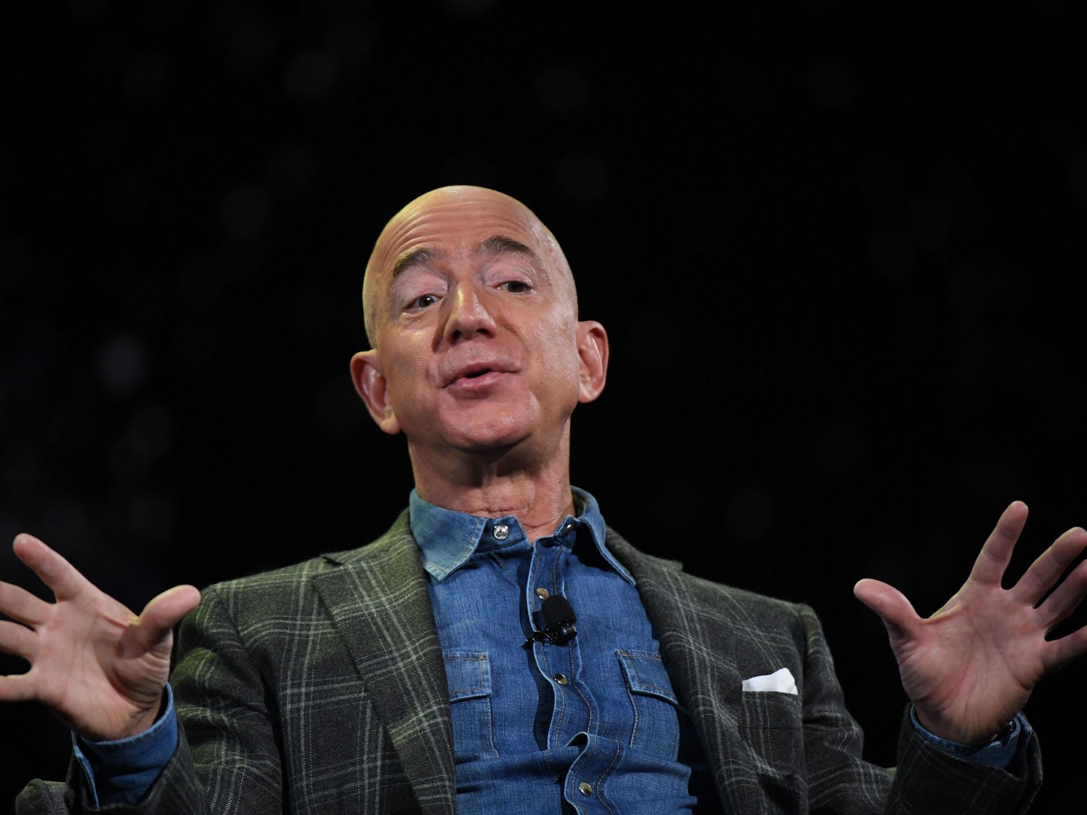 Jeff Bezos holds up hands and raises eyebrows while speaking on stage