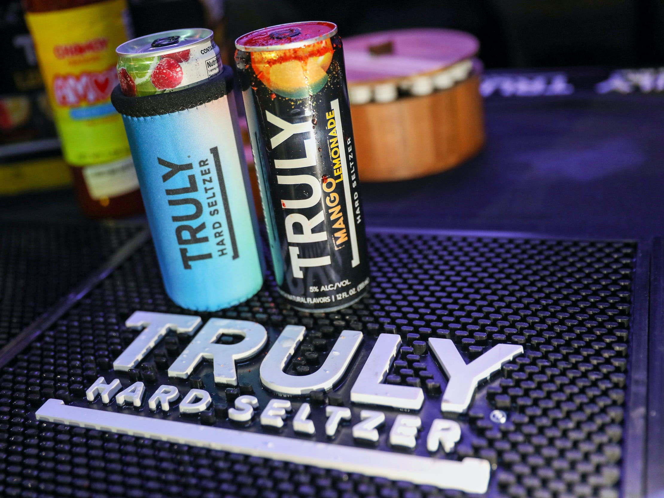 Two cans of Truly hard seltzer sit on bar with Truly-branded mat underneath