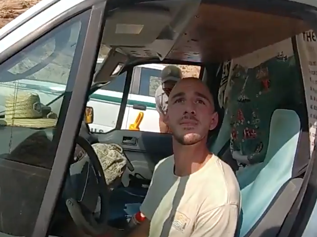 A Utah police officer's bodycam view of Brian Laundrie in the drivers' seat of a van. Laundrie is looking up at the officer.