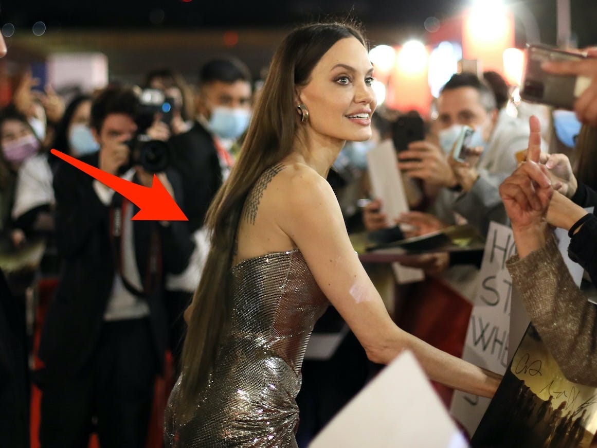 Angelina Jolie greets fans on a red carpet with a red arrow pointing to her hair.