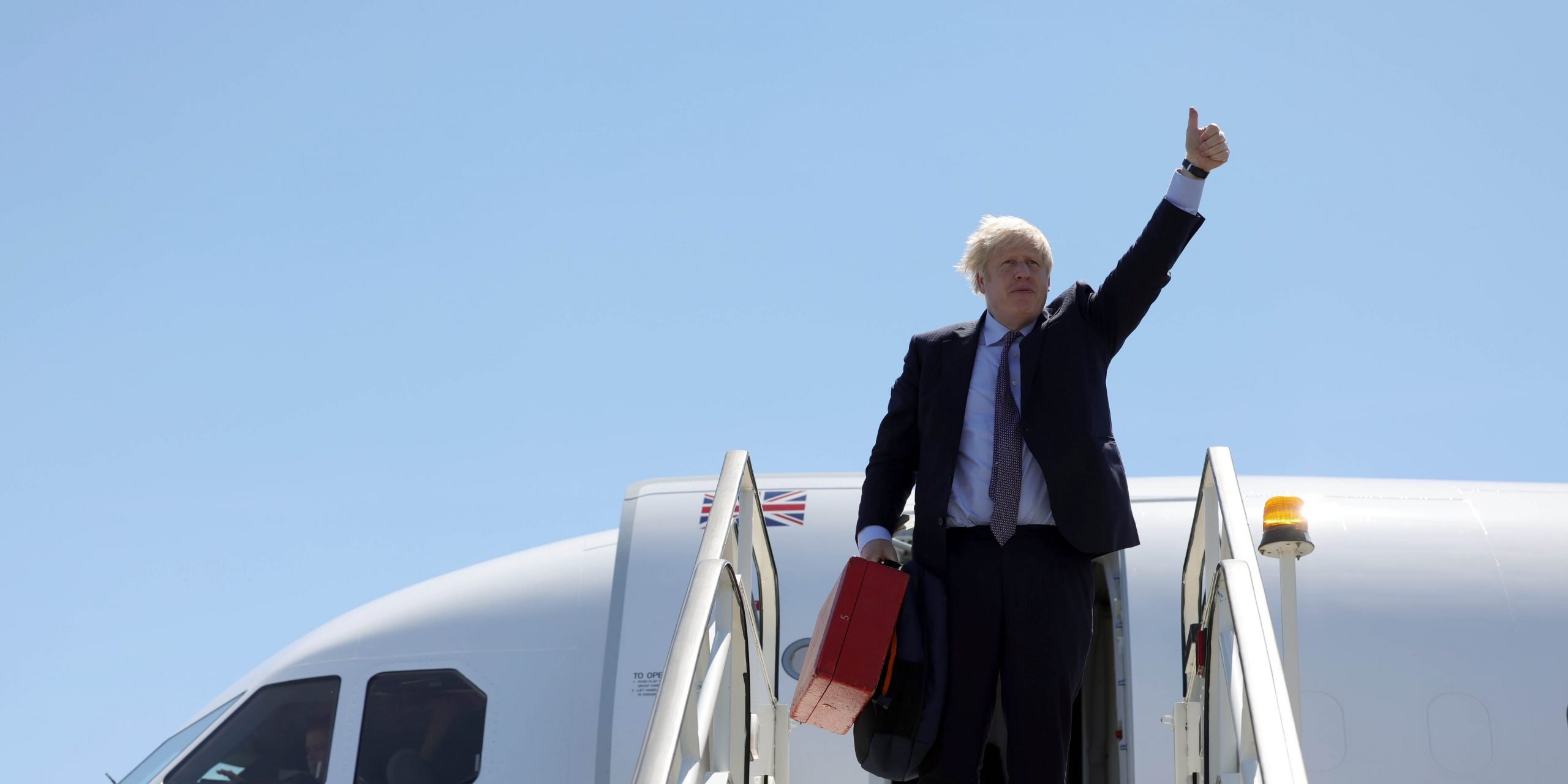 Boris Johnson gives a thumbs-up from the steps of an aircraft