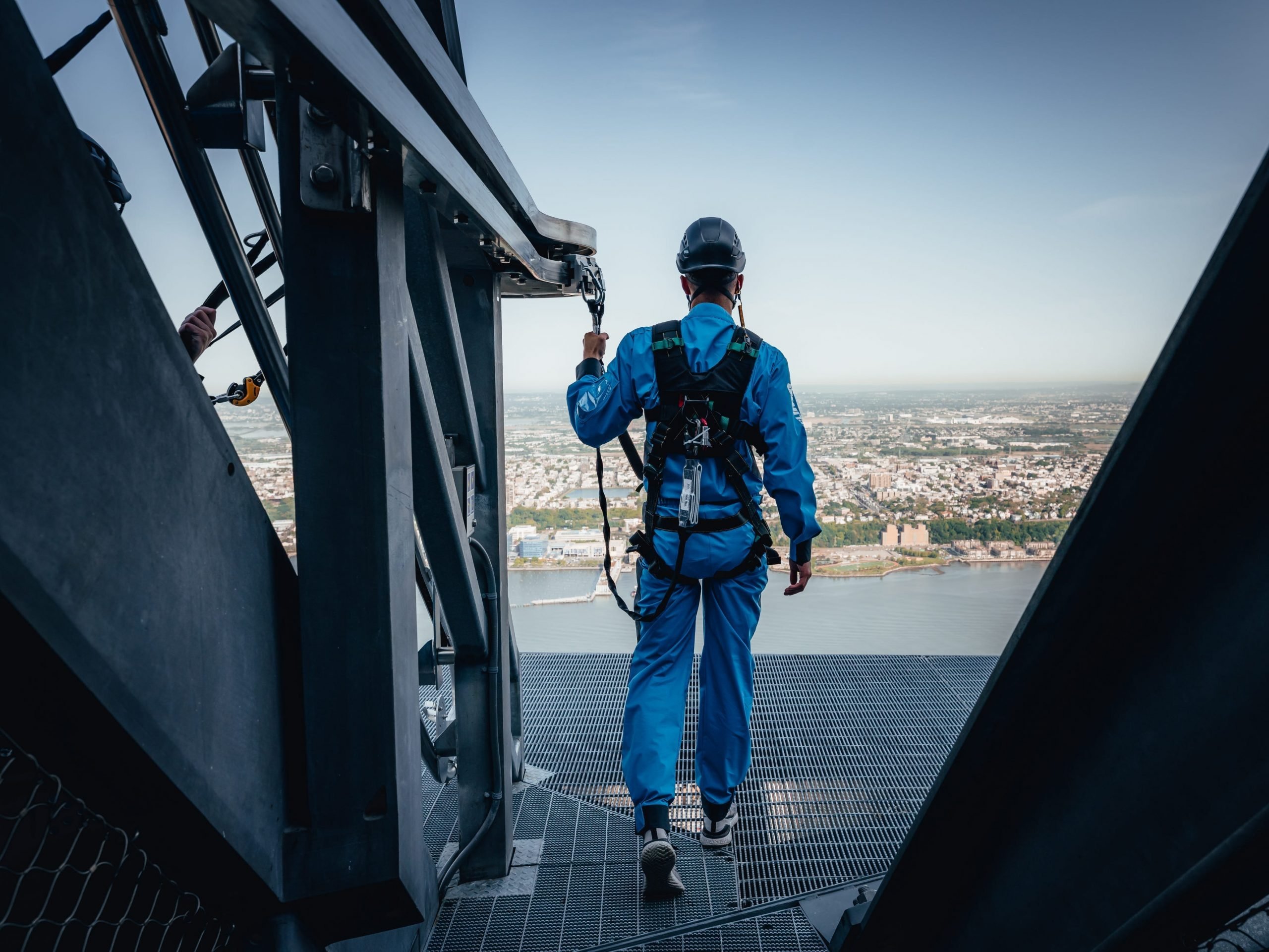 A city climber in a blue jumpsuit looks out over the view.