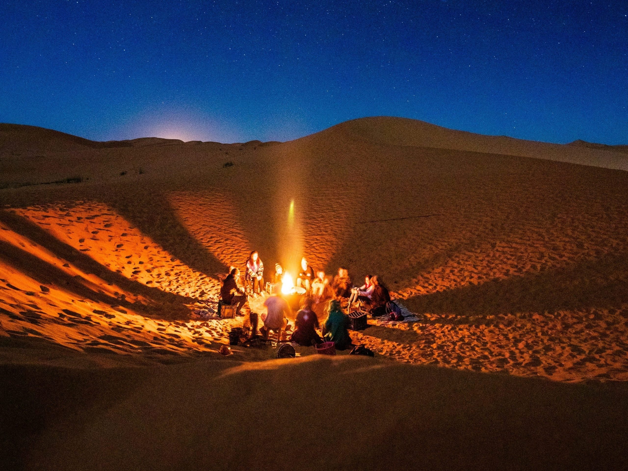 a group of people around a campfire in the desert